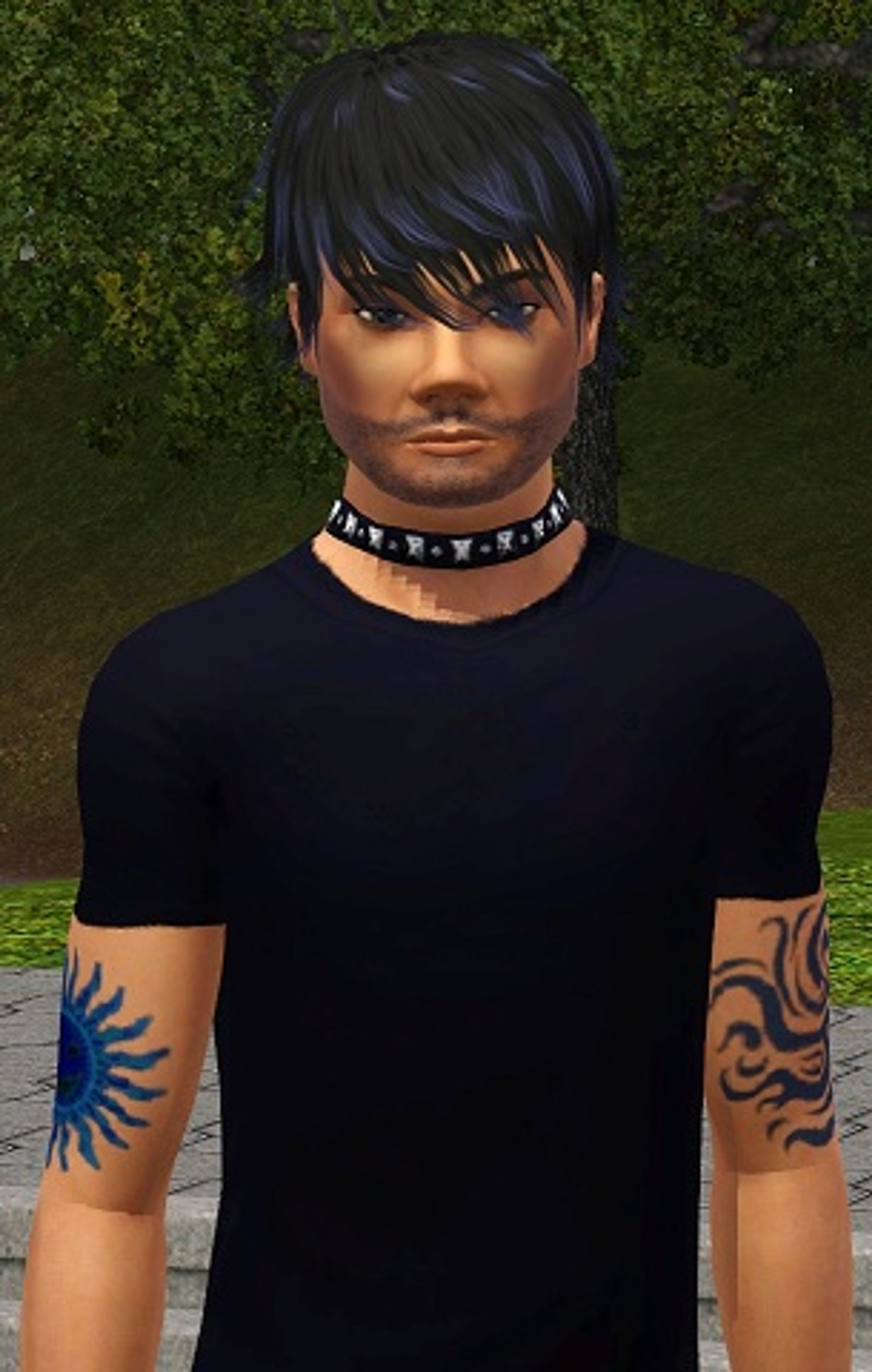 A young man with dark hair, tattoos, and a black t-shirt in an outdoor setting.