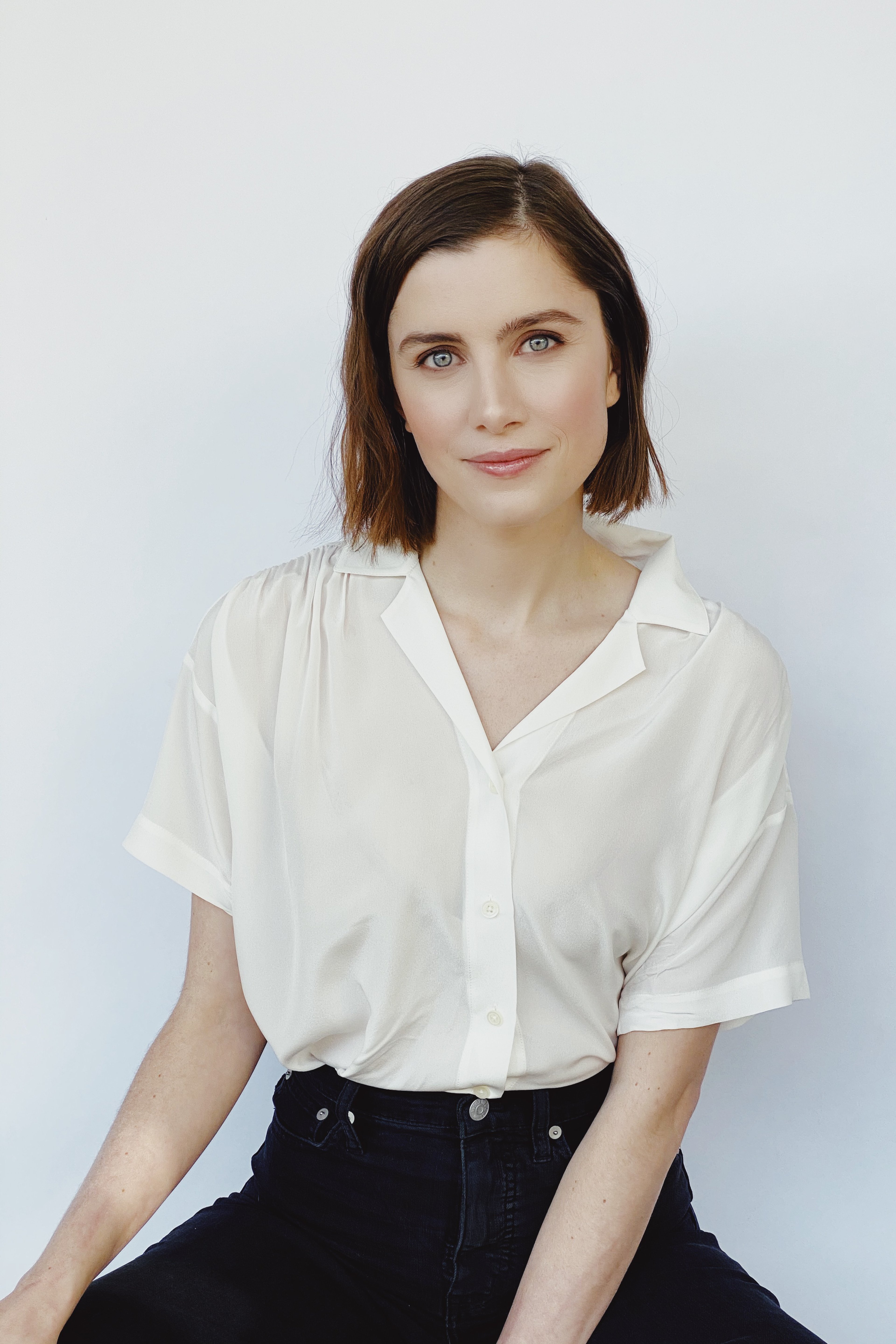 A young woman with dark hair wearing a white blouse