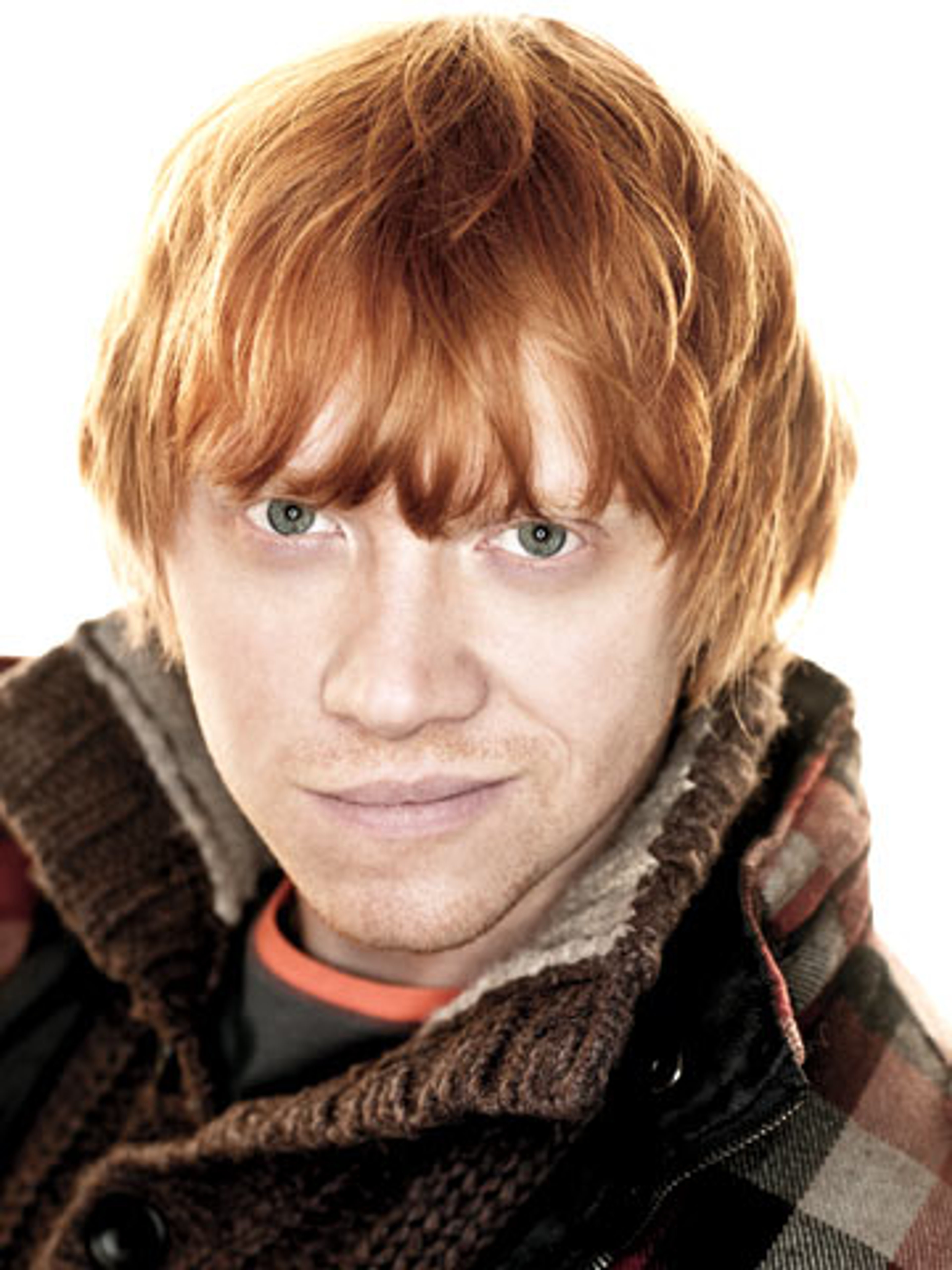 A young man with red hair and freckles, wearing a brown sweater and scarf.