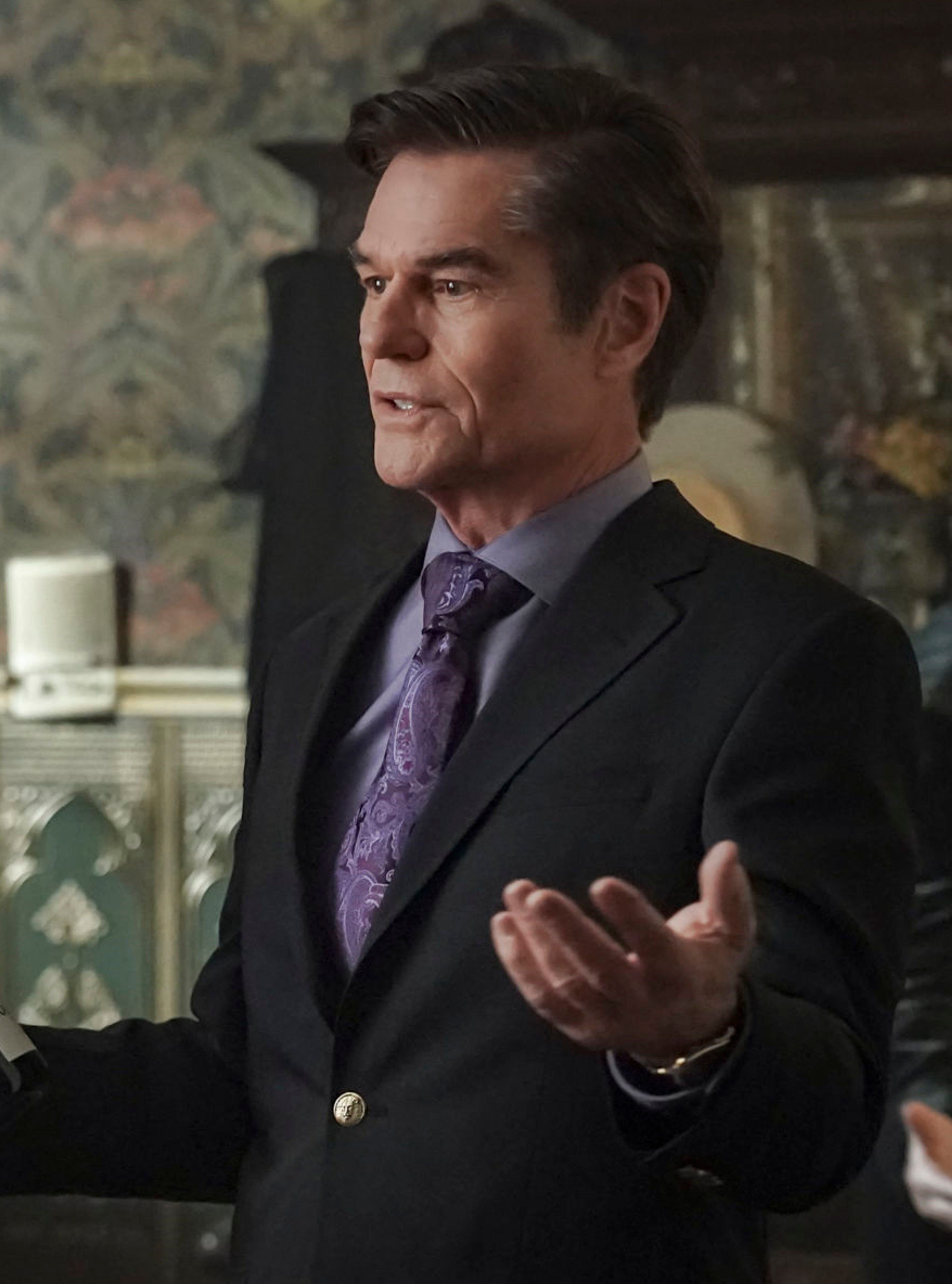 A well-dressed, middle-aged man with a confident, charismatic expression