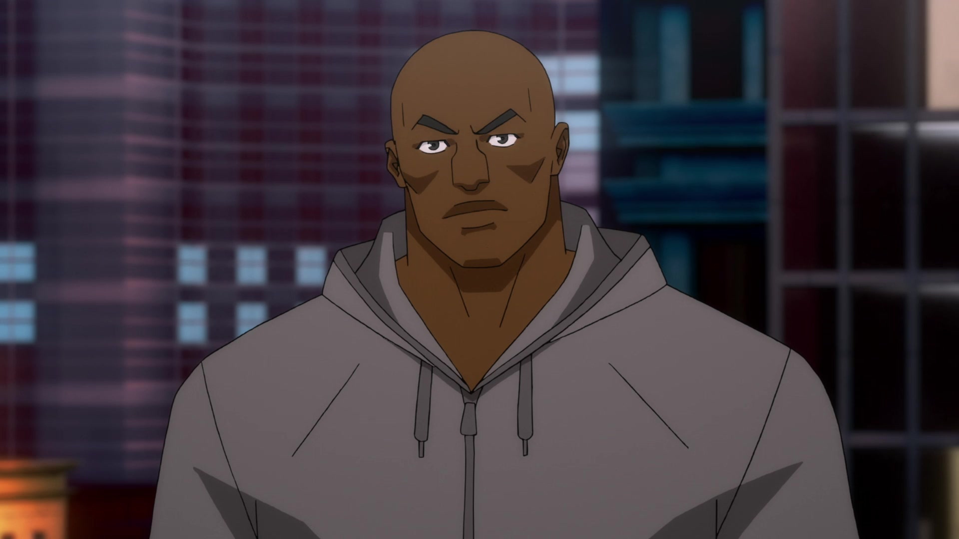 A muscular, bald African-American man with a stern expression, wearing a gray hooded sweatshirt.