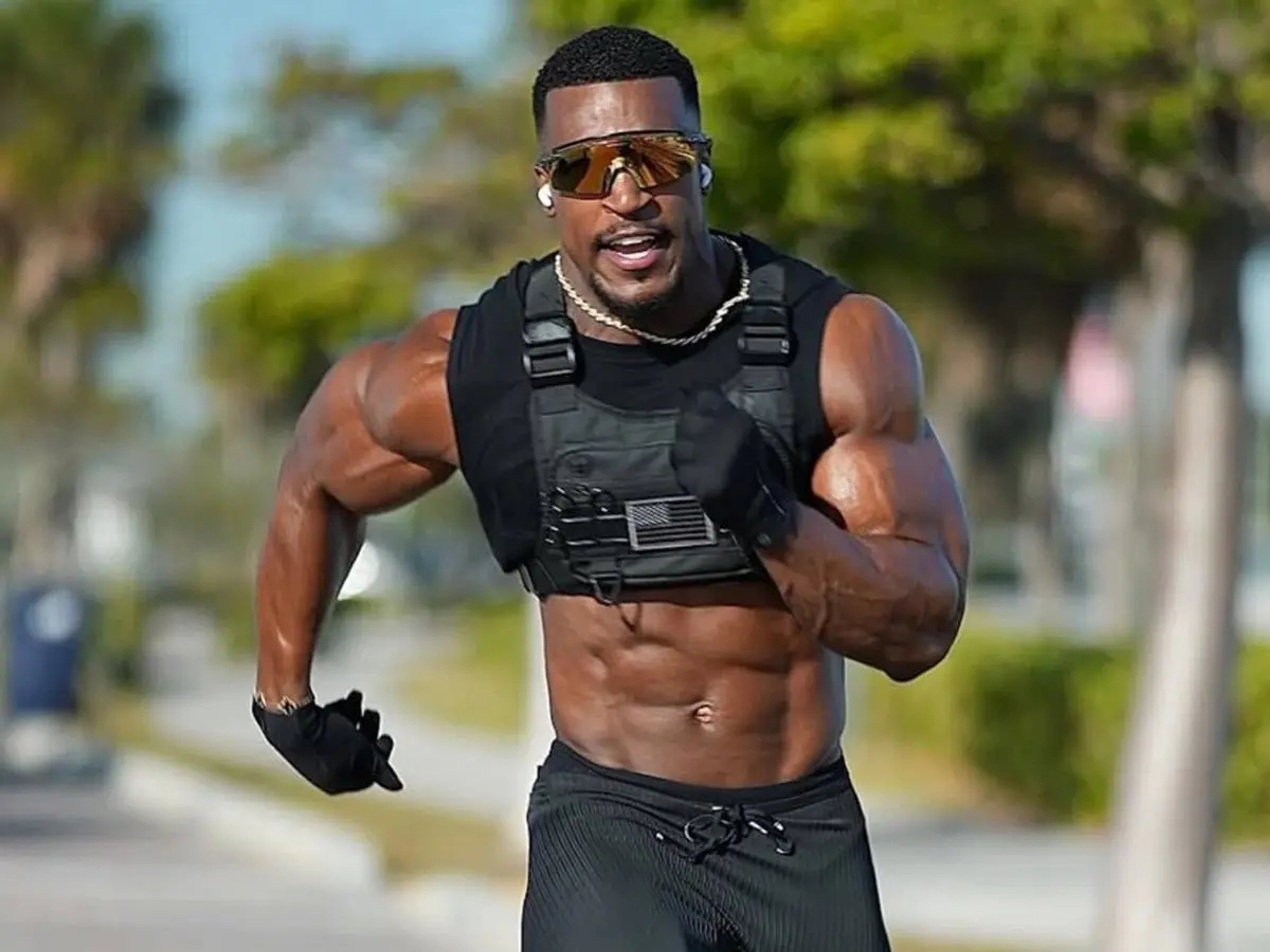 A muscular, shirtless man posing confidently in athletic wear