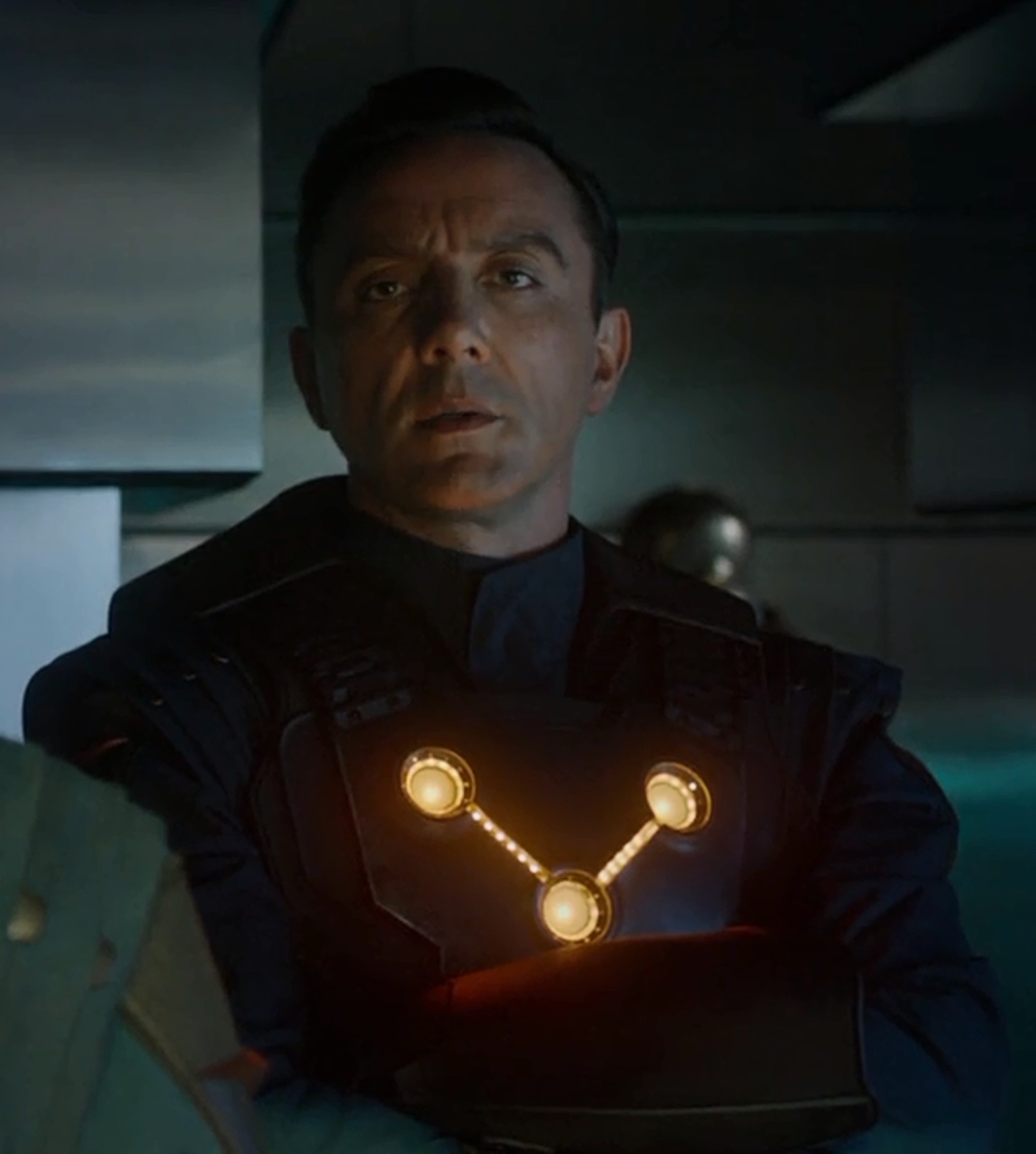 A man in a dark uniform with glowing lights on the chest