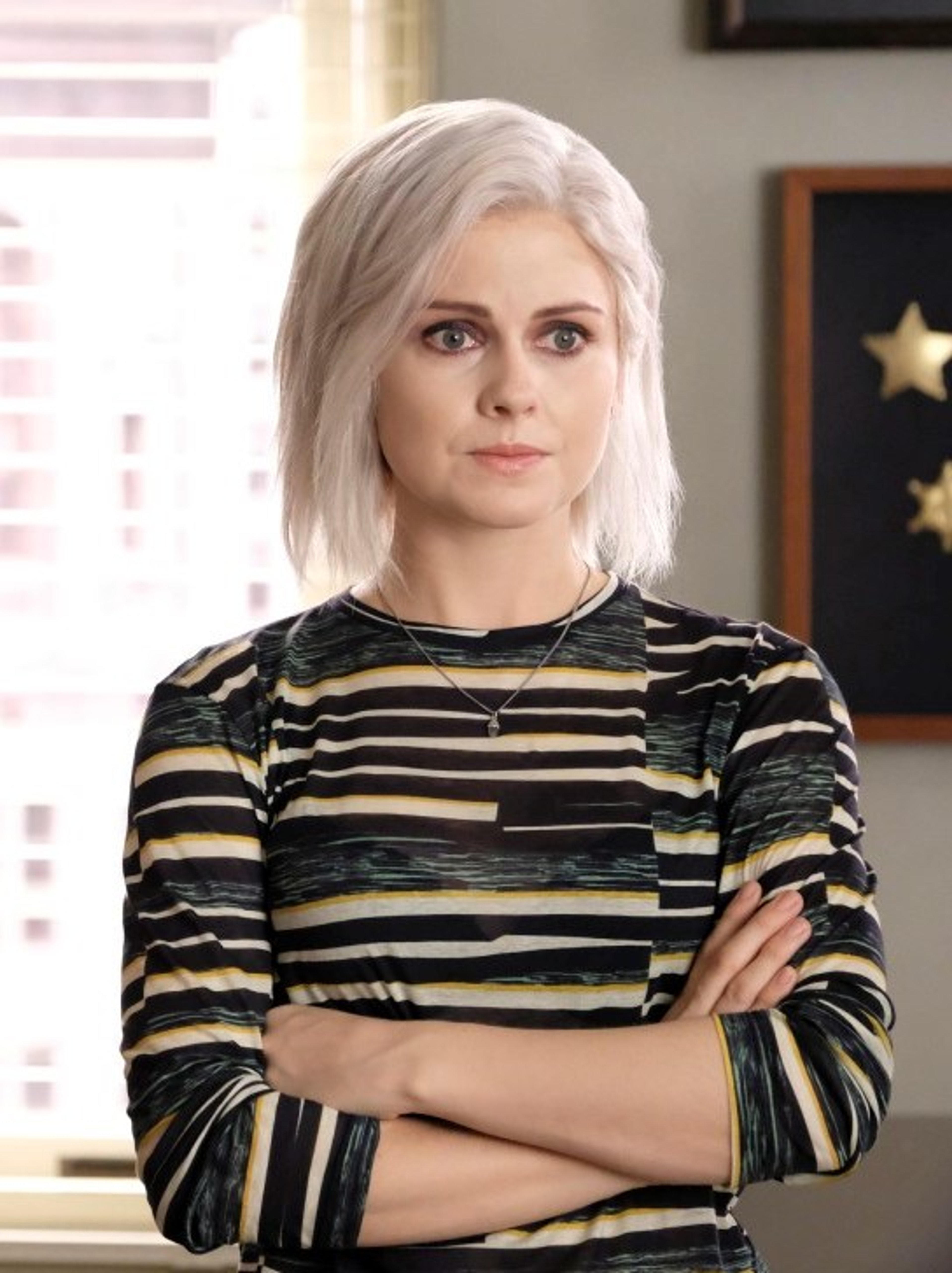A young woman with short, platinum blonde hair wearing a black and white striped top