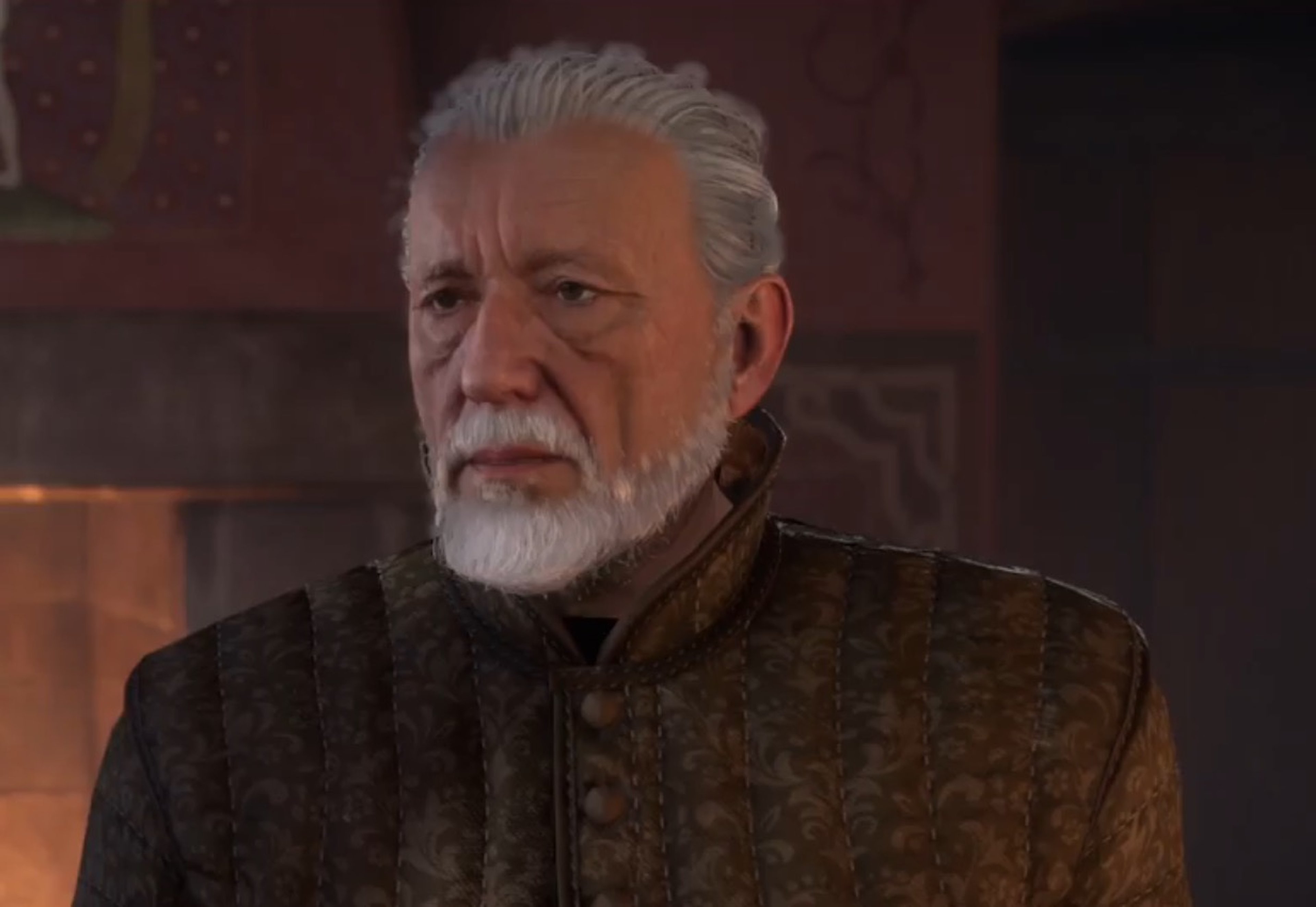 An older man with a gray beard wearing a green tunic with gold embroidery