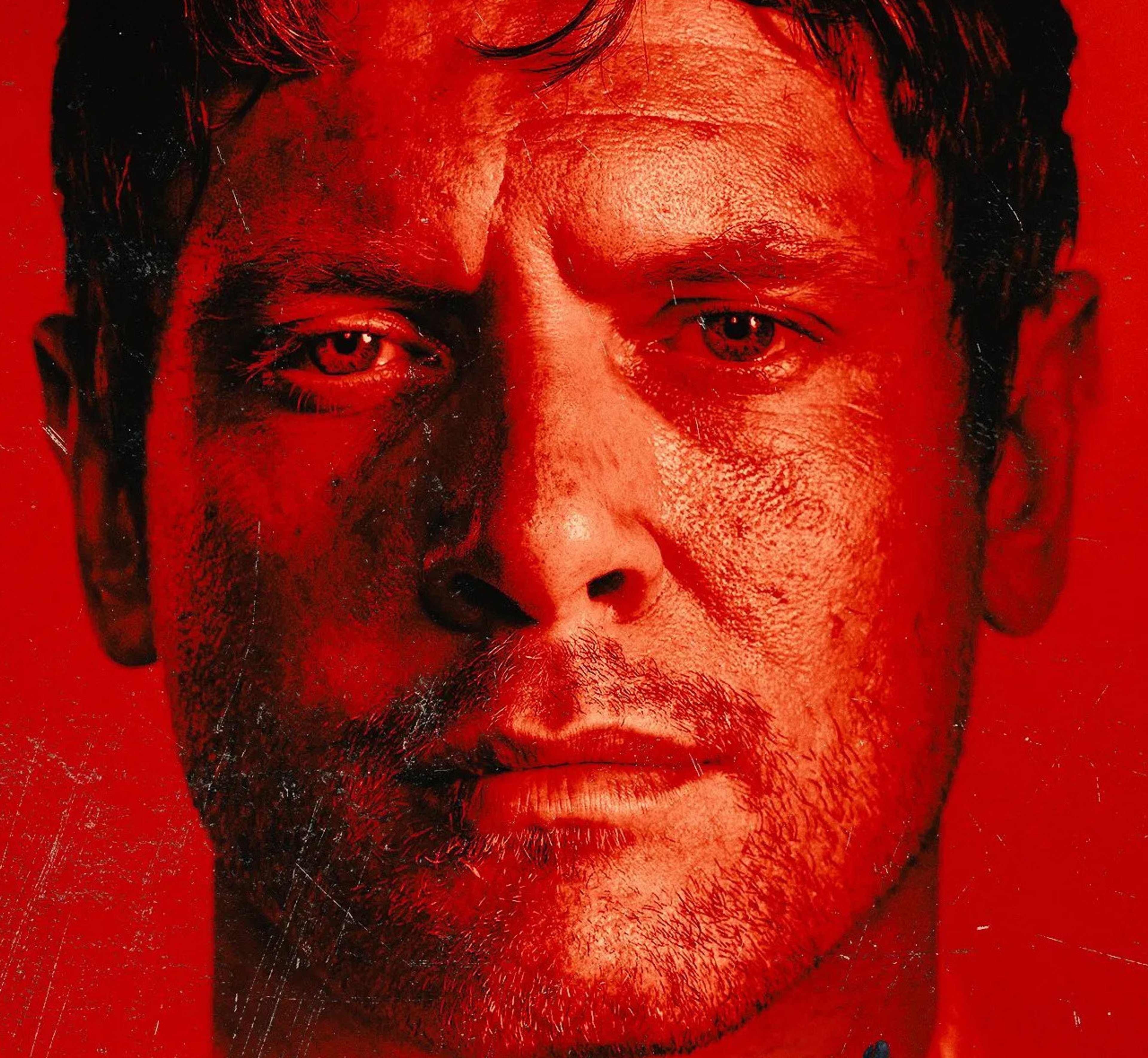 A close-up portrait of a man with intense red eyes and a rugged, serious expression