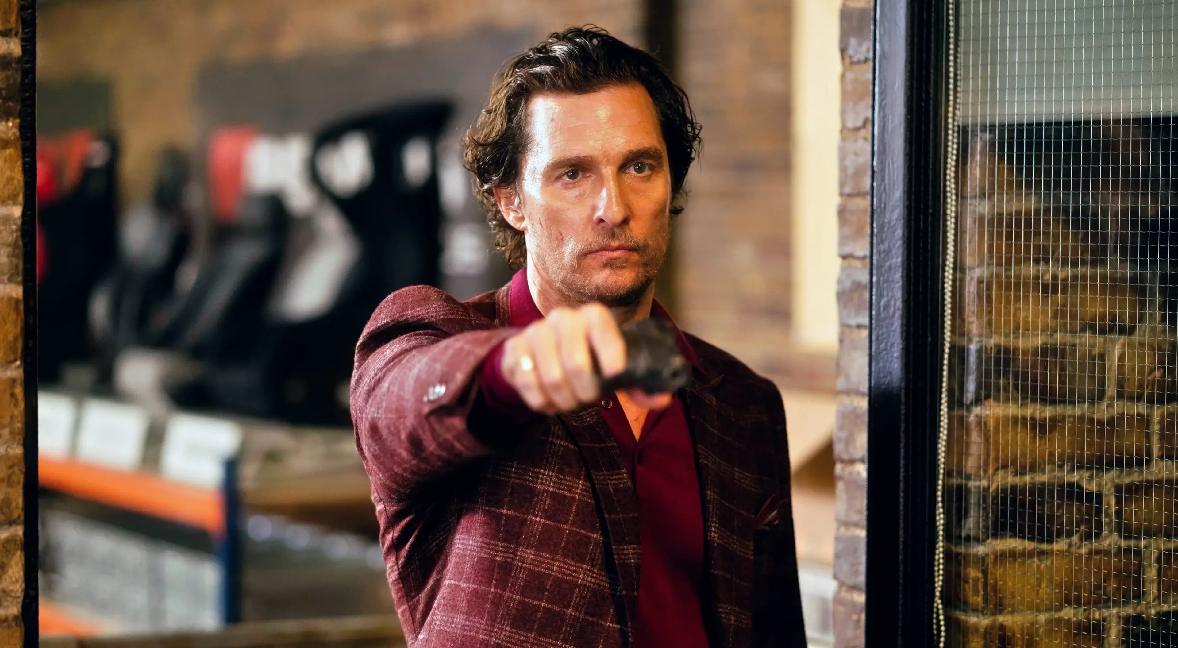 A middle-aged man with a beard wearing a red plaid shirt in an urban setting