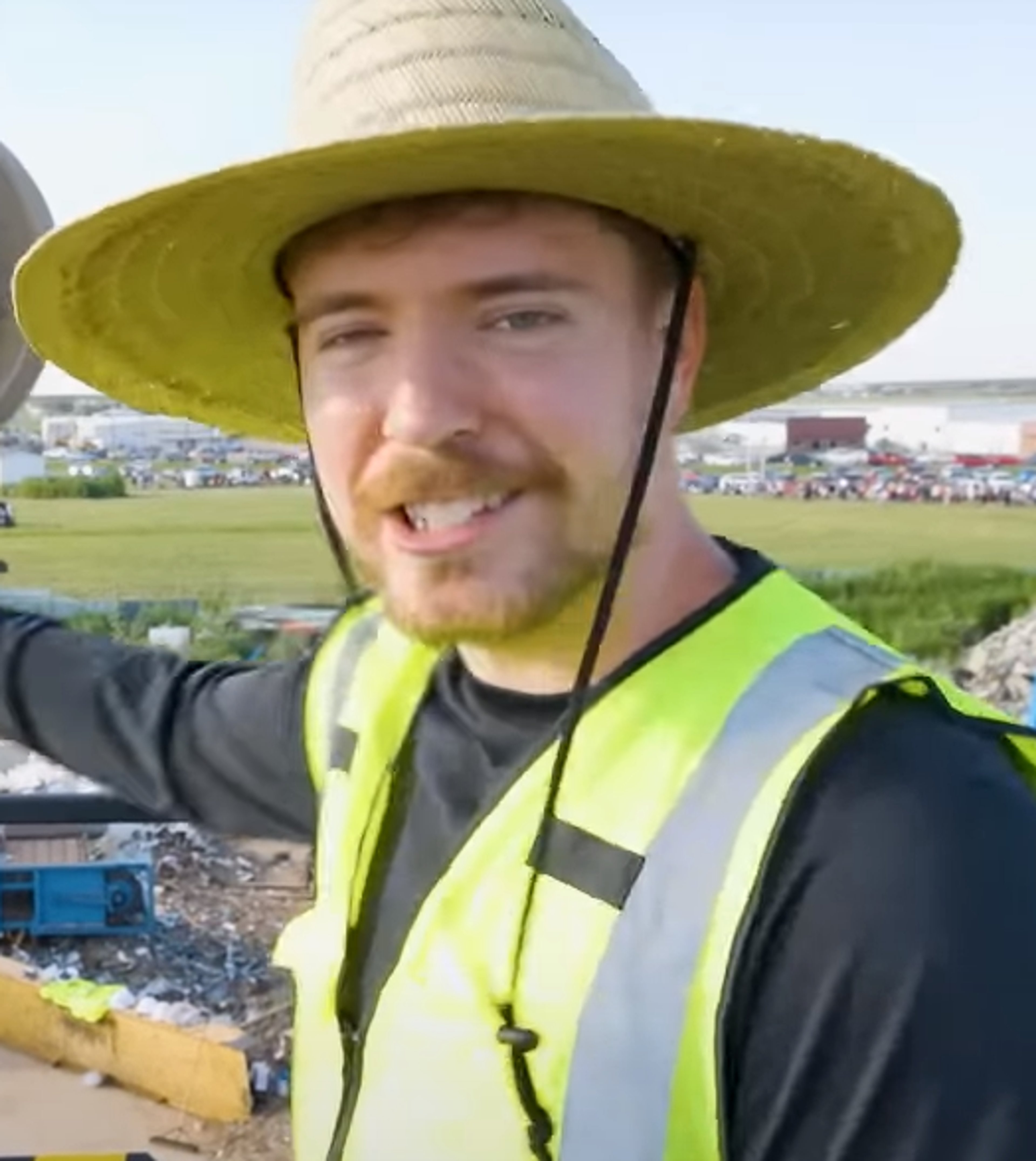 A man in a yellow hat and high-visibility vest smiling at the camera