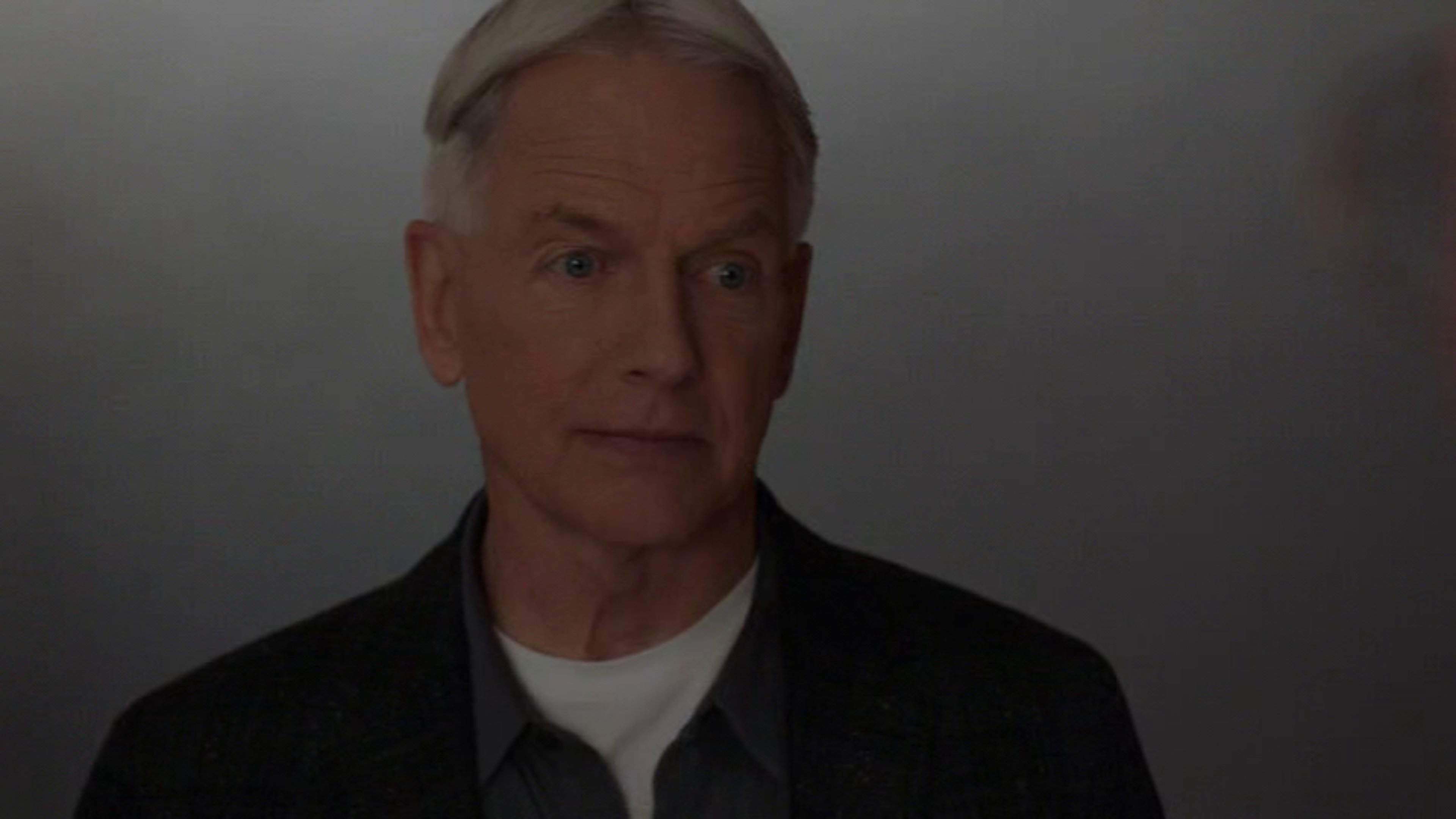 A middle-aged man with short gray hair wearing a dark suit and tie, with a serious expression on his face.