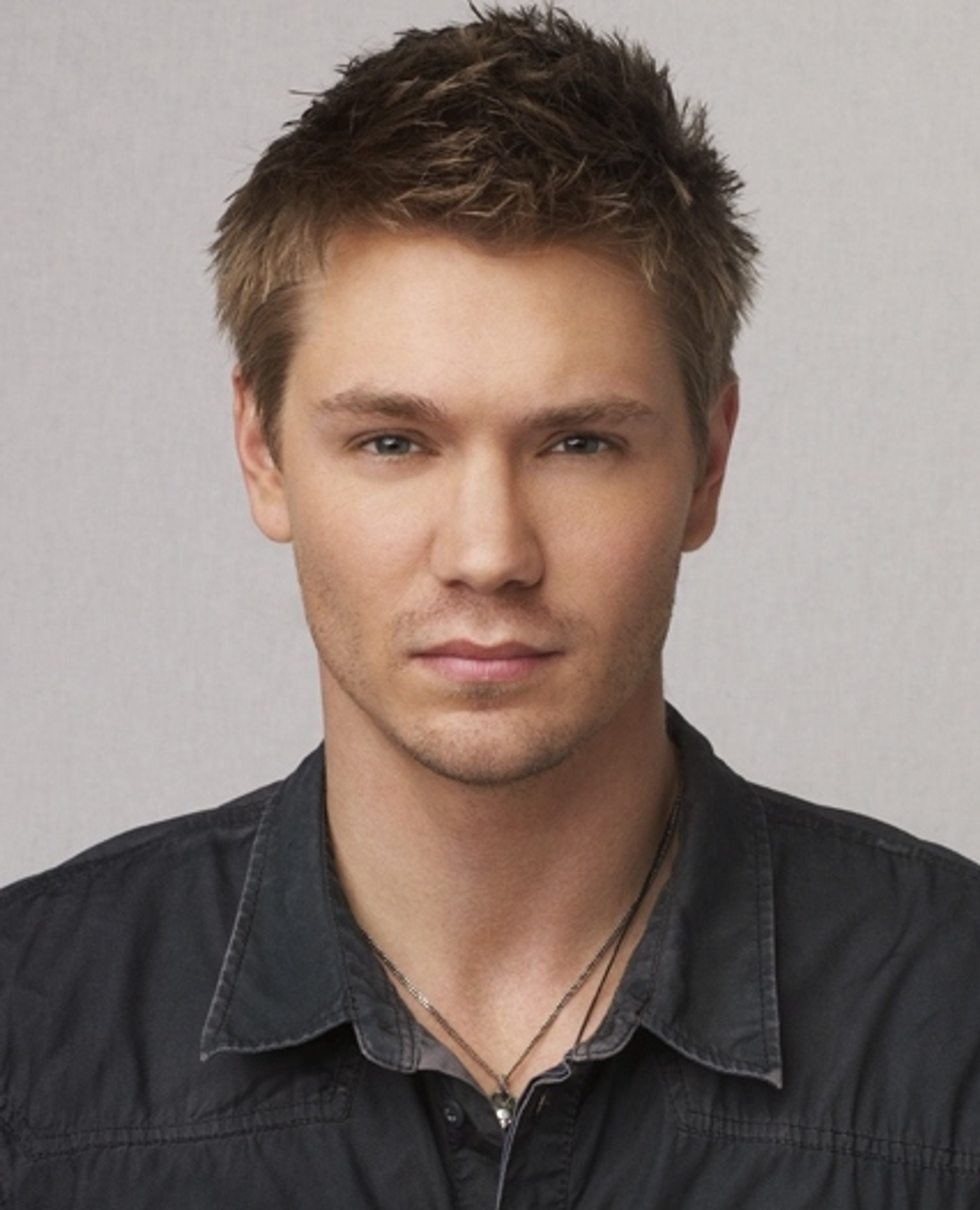 A young man with short dark hair wearing a gray shirt