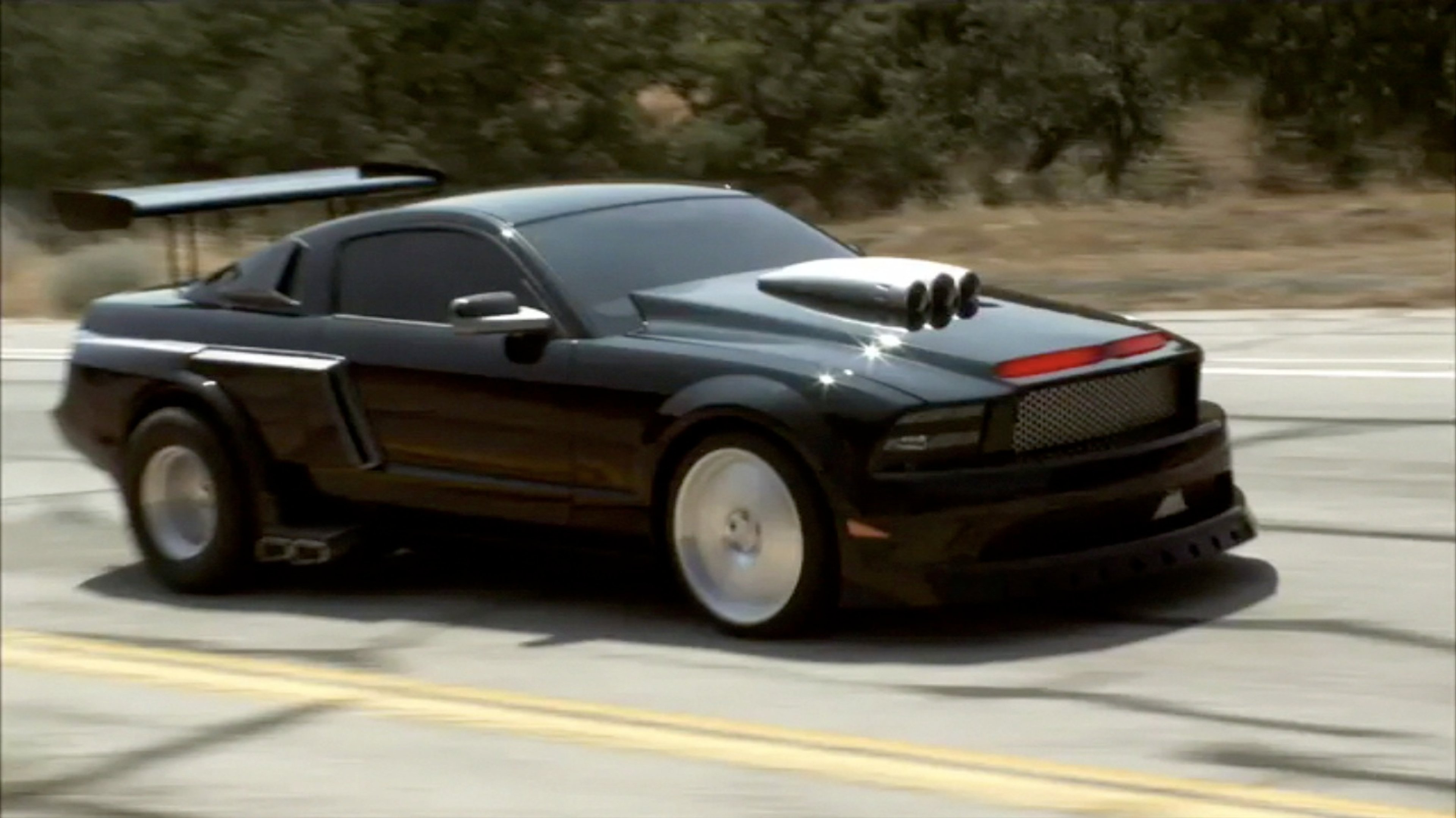 A high-tech, black sports car with red accents, speeding down a road.