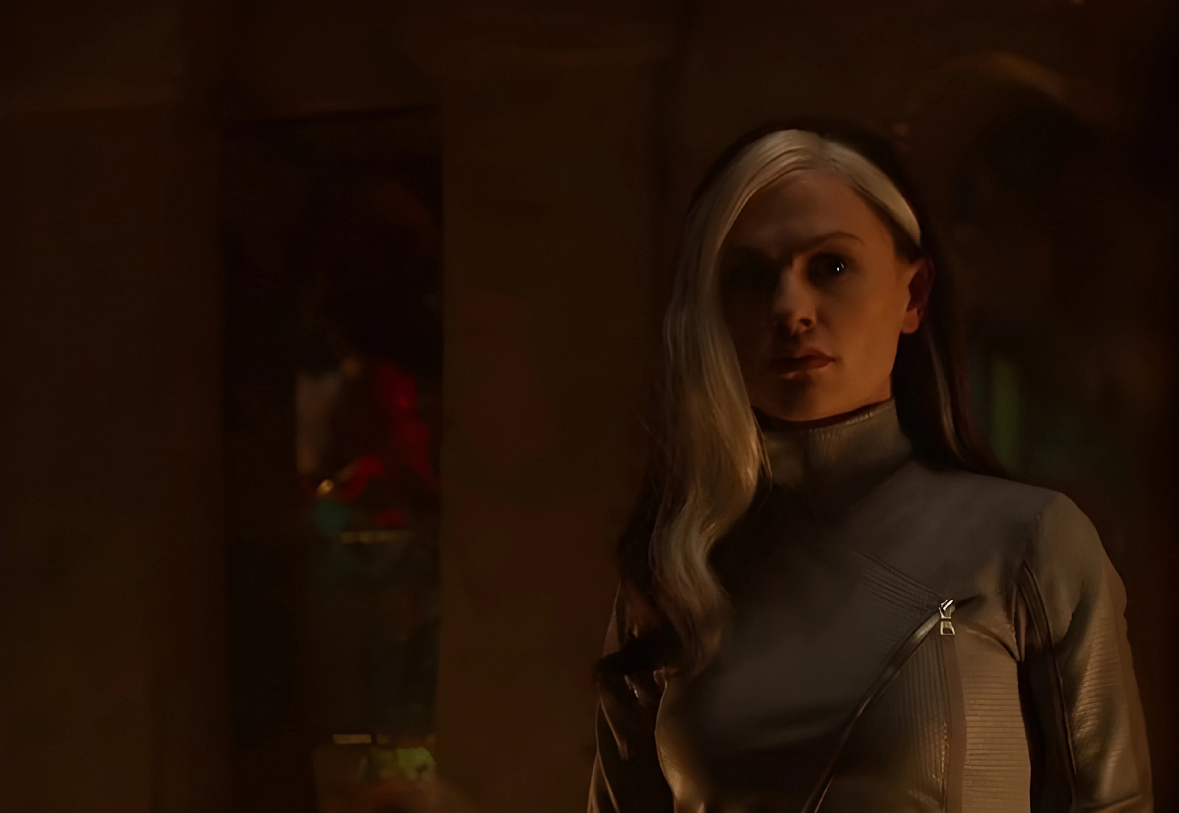 A young woman with white streaks in her hair wearing a dark, high-collared outfit