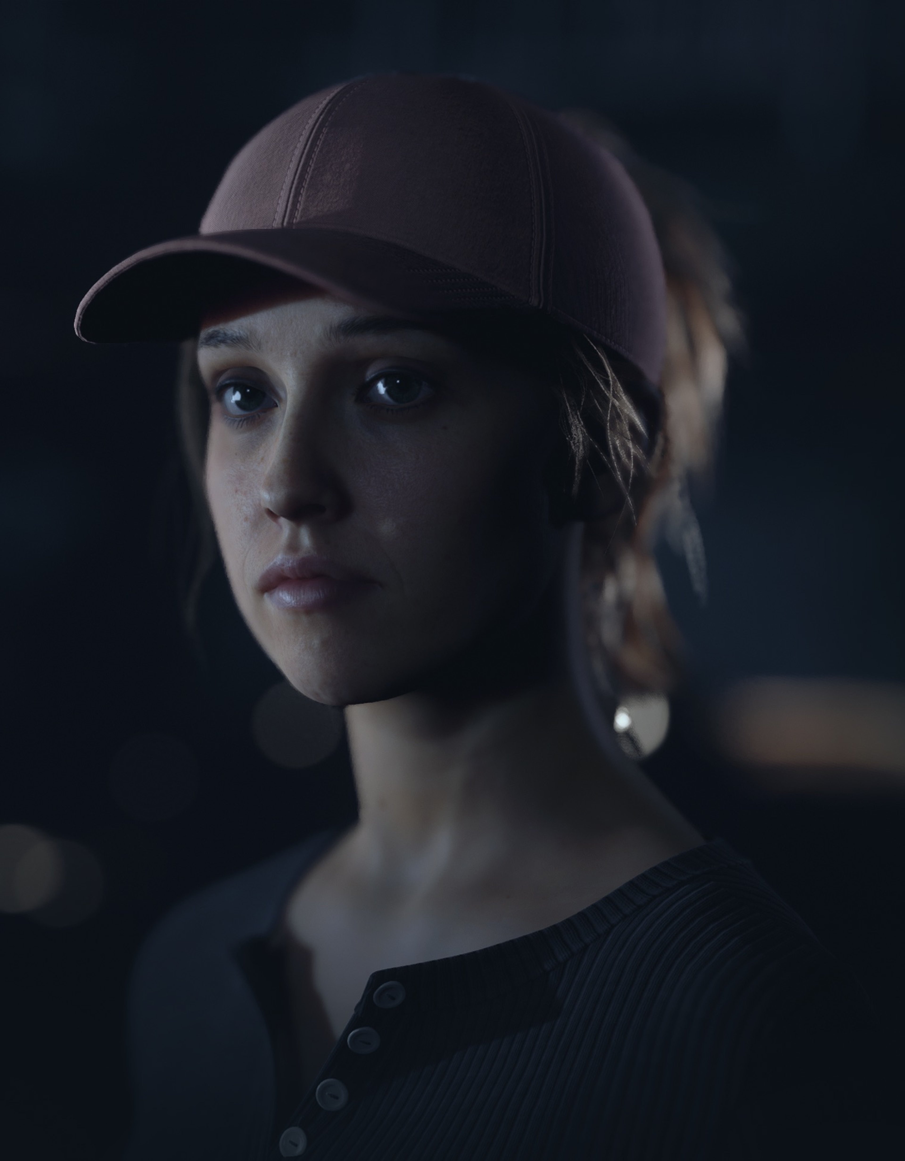 A young woman with dark hair wearing a baseball cap, looking serious and determined.