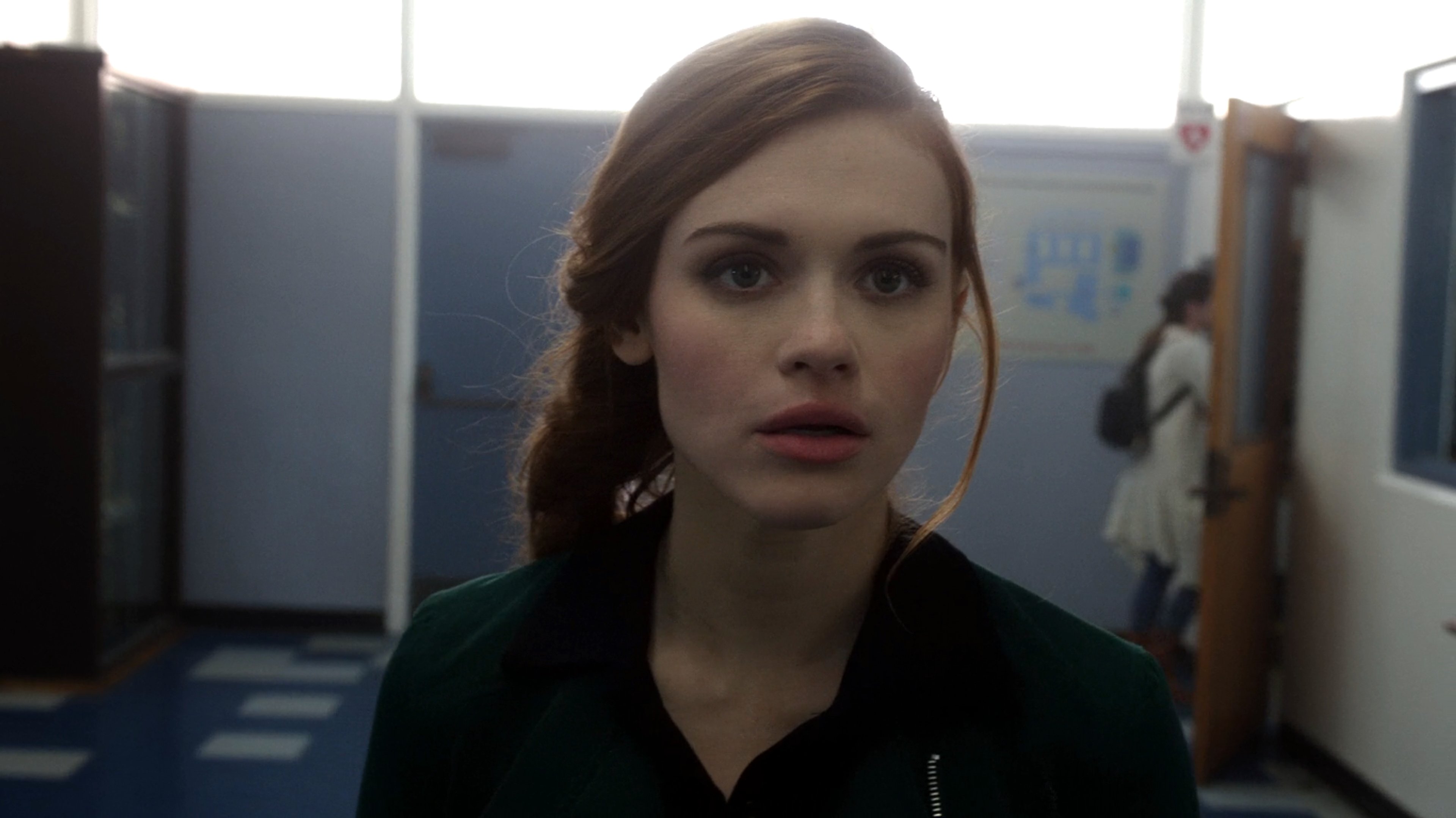 A young woman with long brown hair and green eyes wearing a black jacket