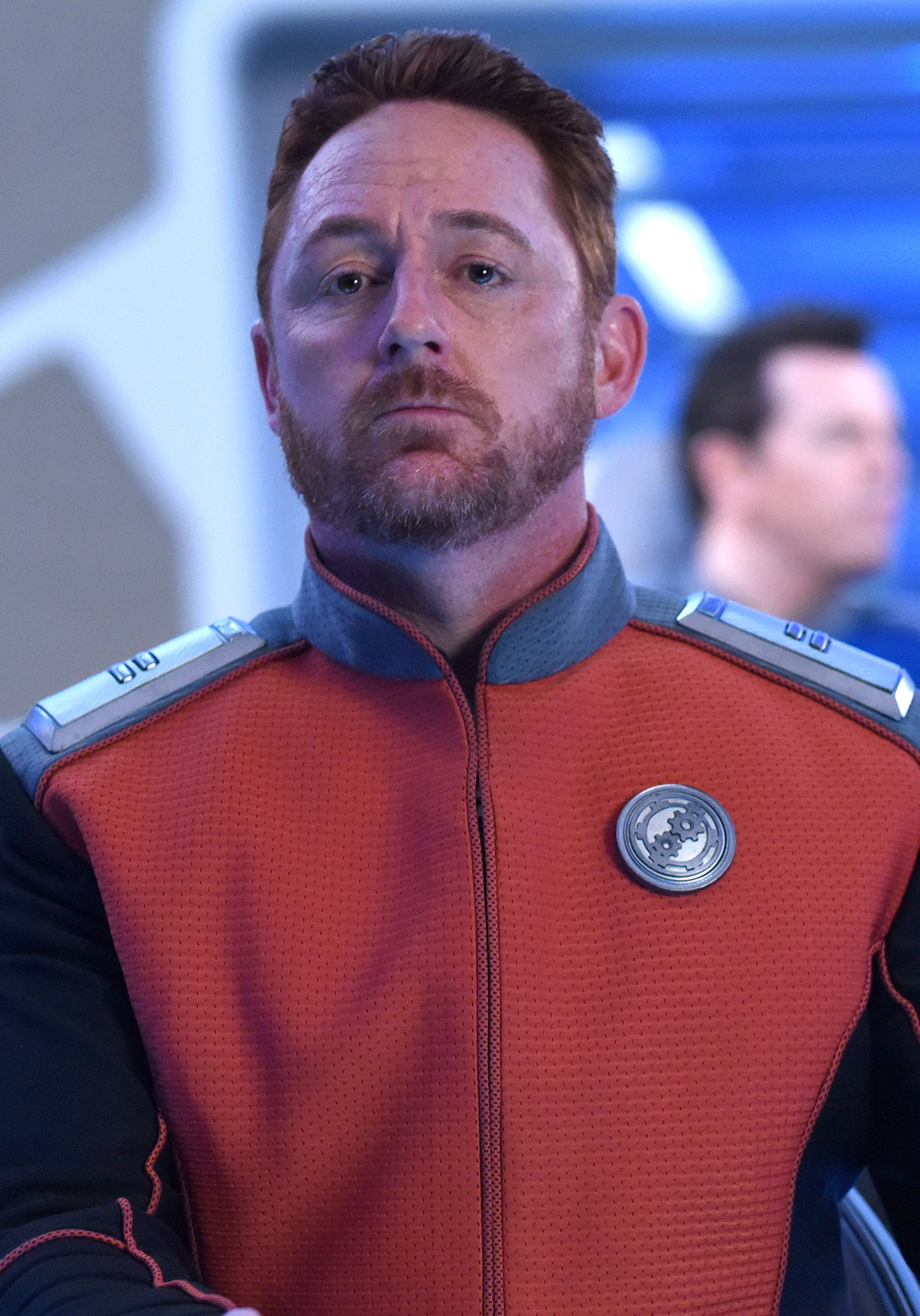 A man in a red and black uniform with a Planetary Union insignia