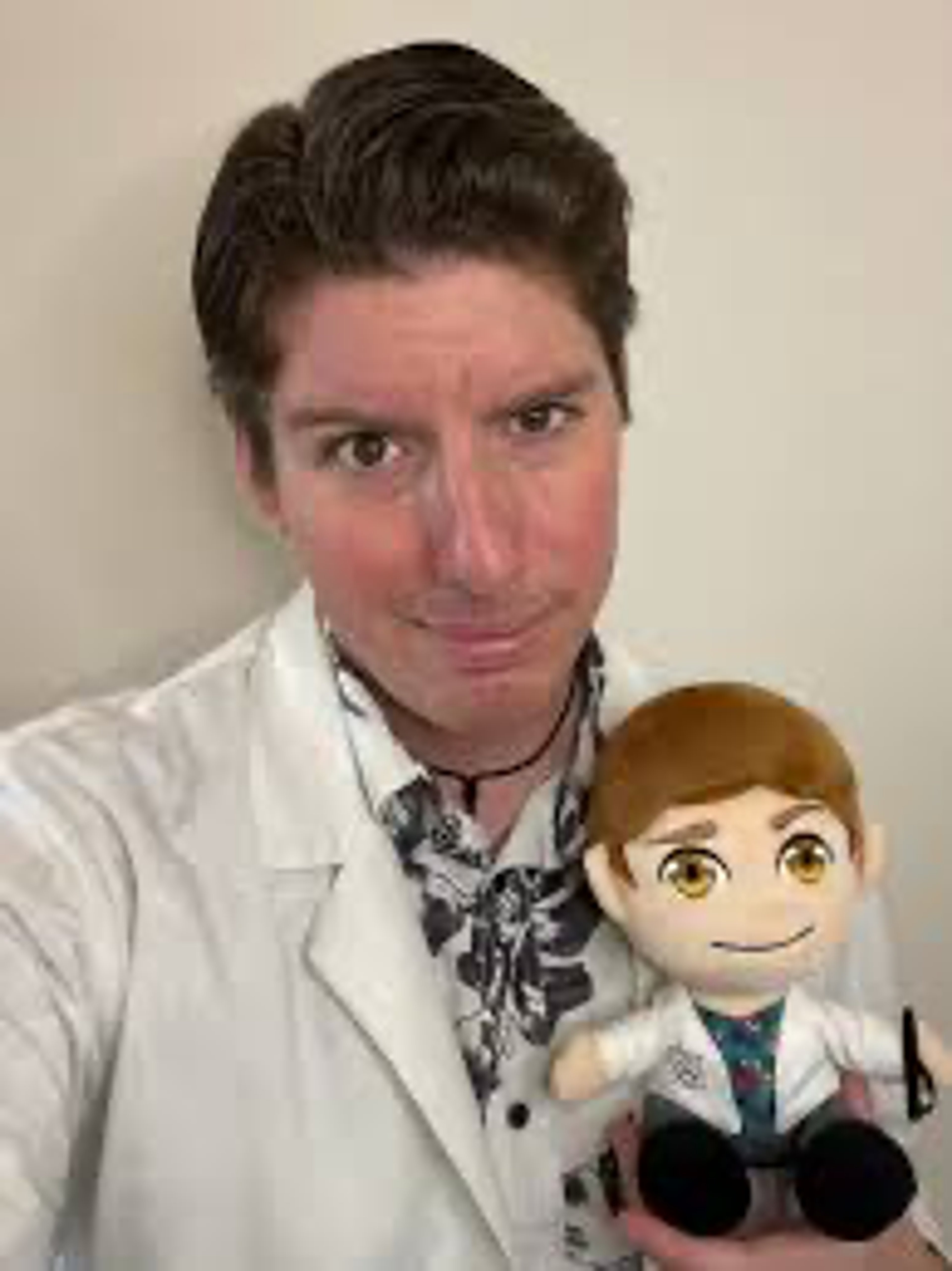 A man in a lab coat holding a plush toy