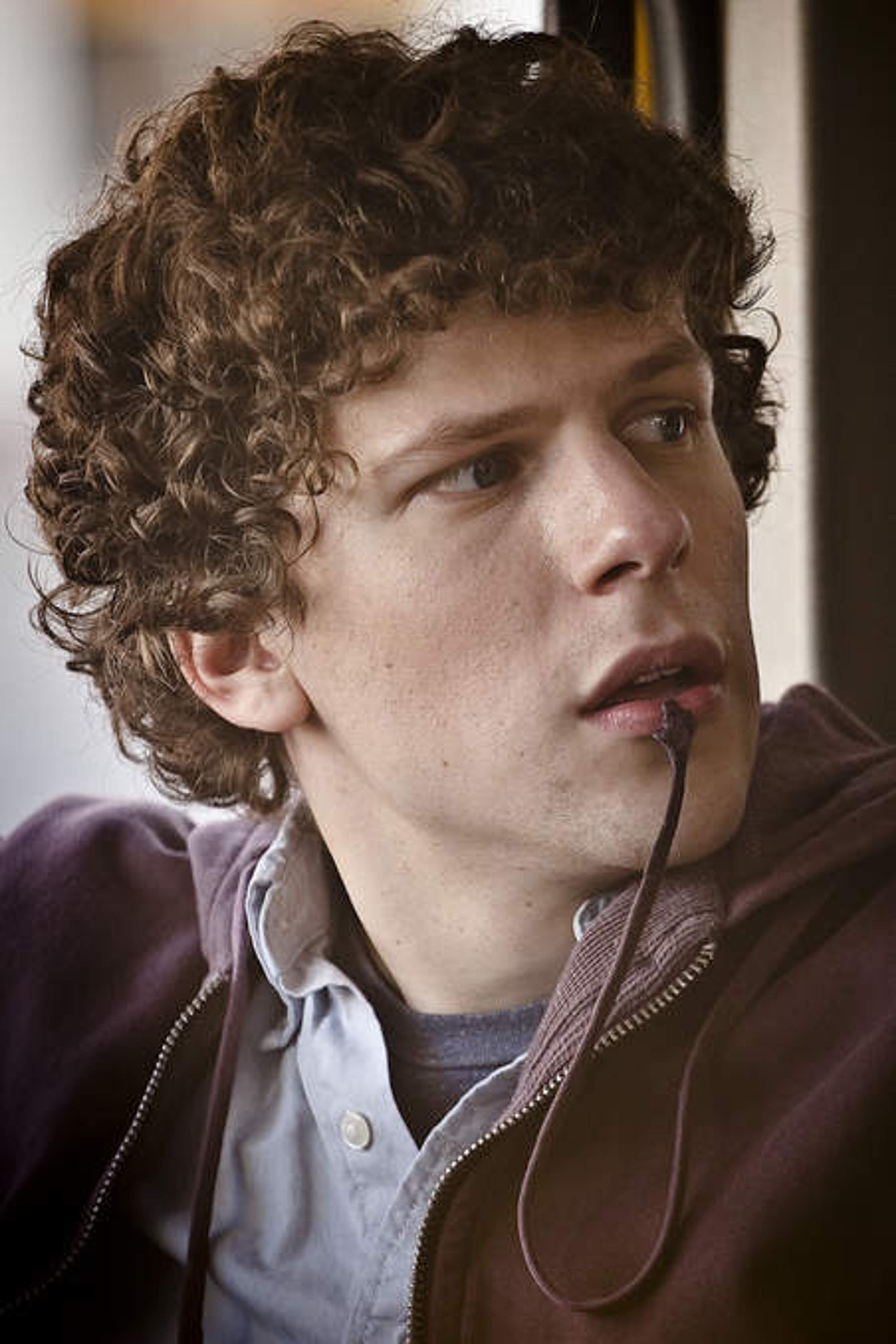 A young man with curly brown hair and blue eyes wearing a purple hooded sweatshirt