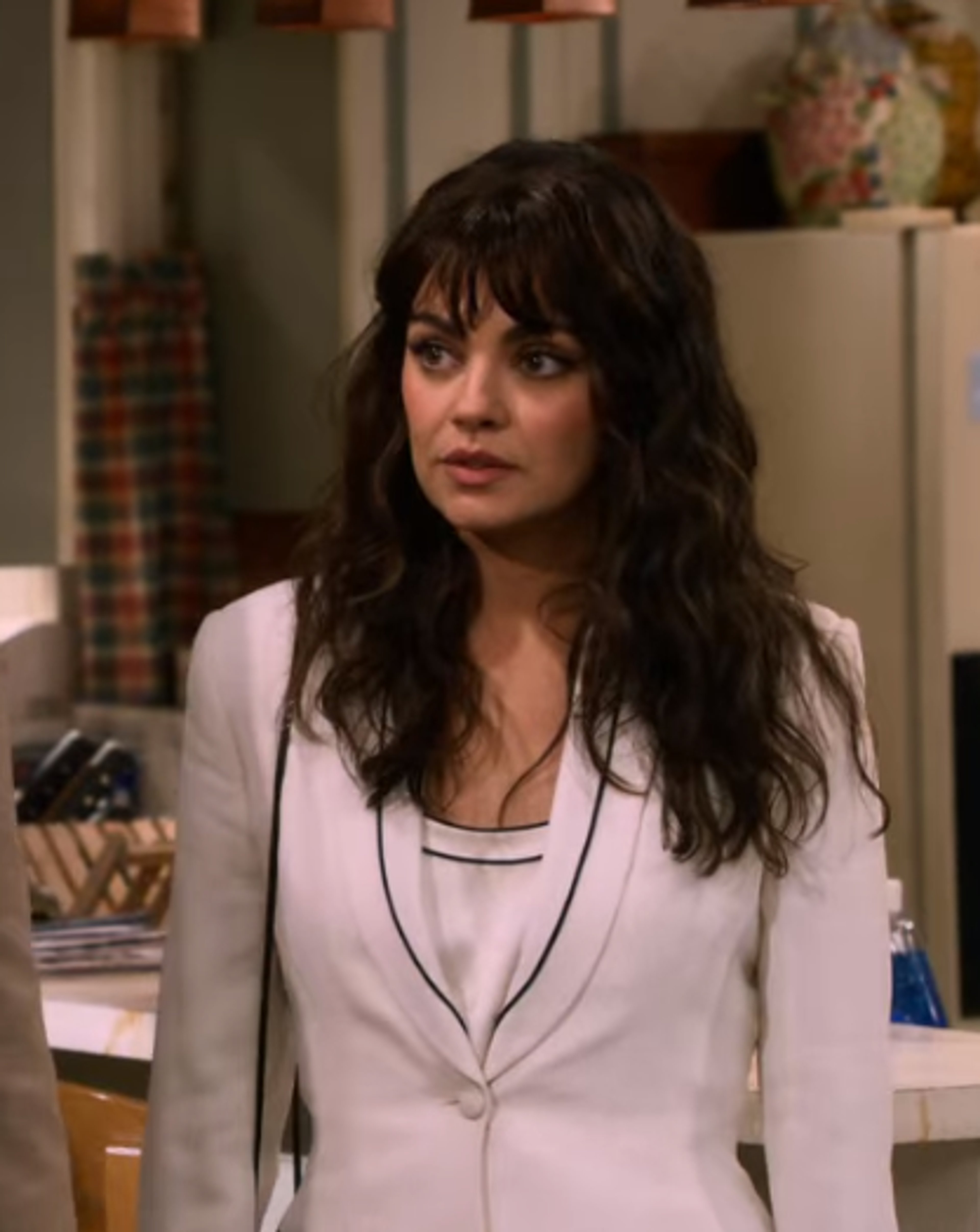 A young woman with long dark hair wearing a light-colored blazer