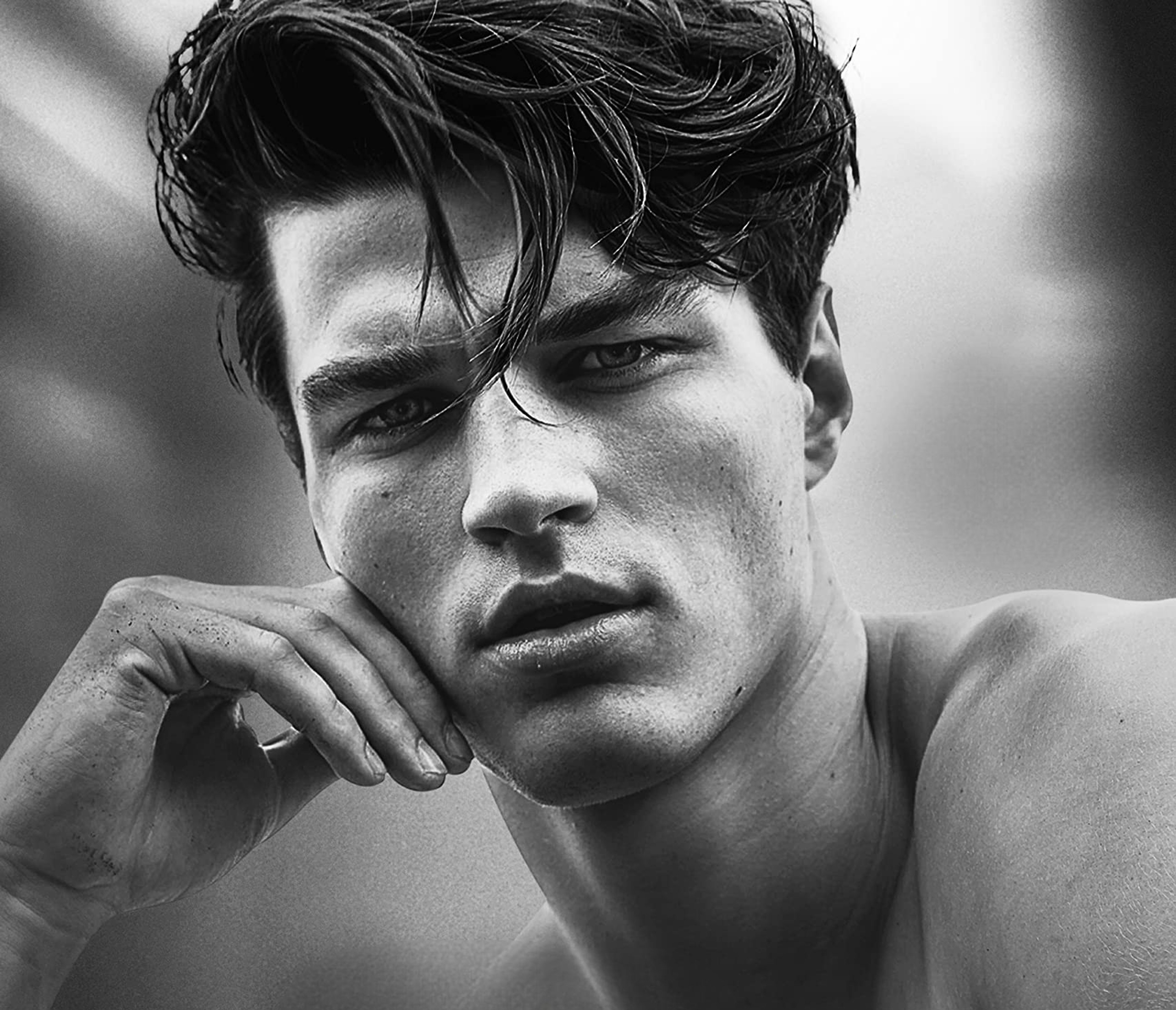 A brooding, intense-looking man with striking blue eyes and messy brown hair