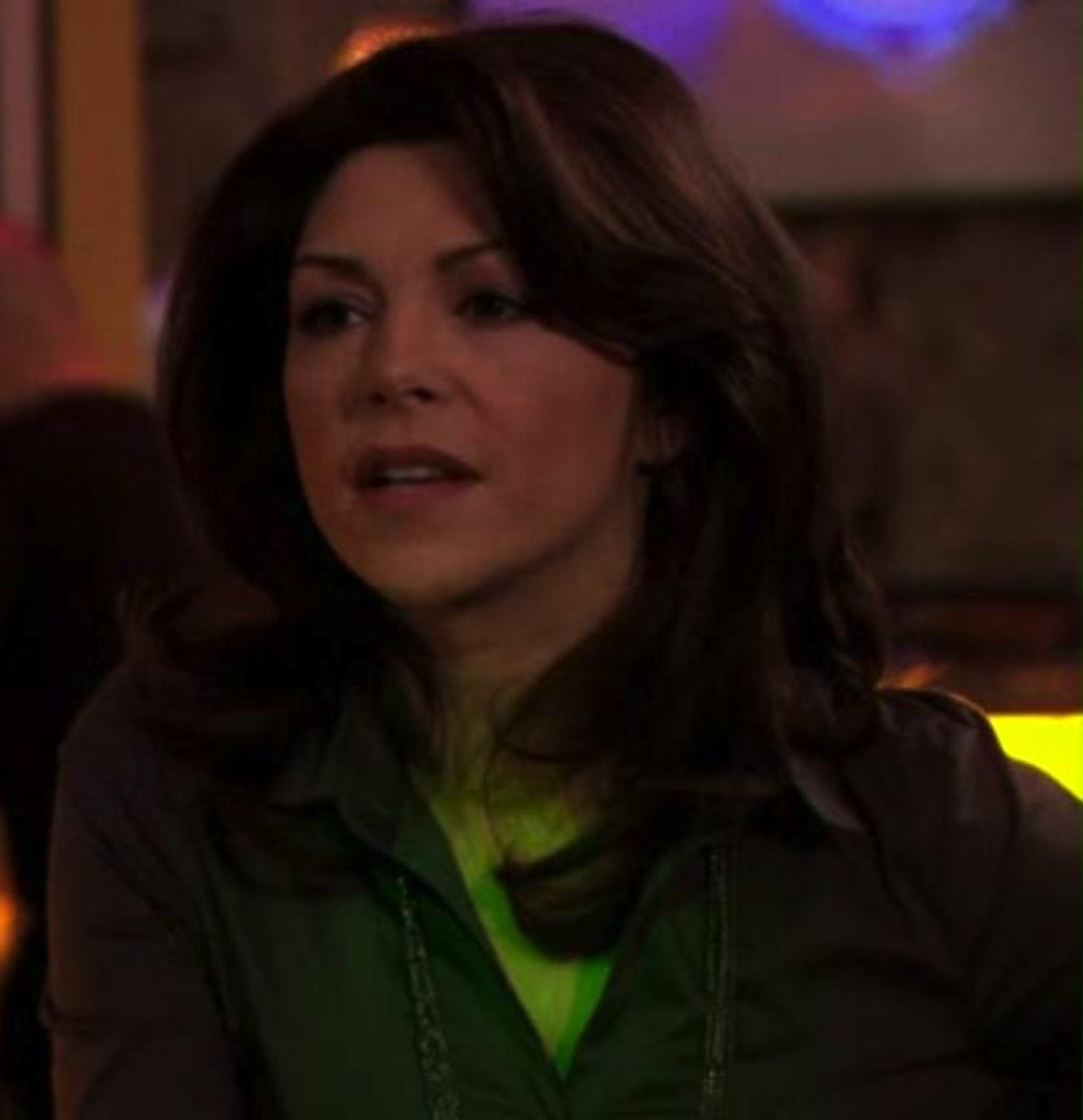 A woman with dark hair wearing a green top