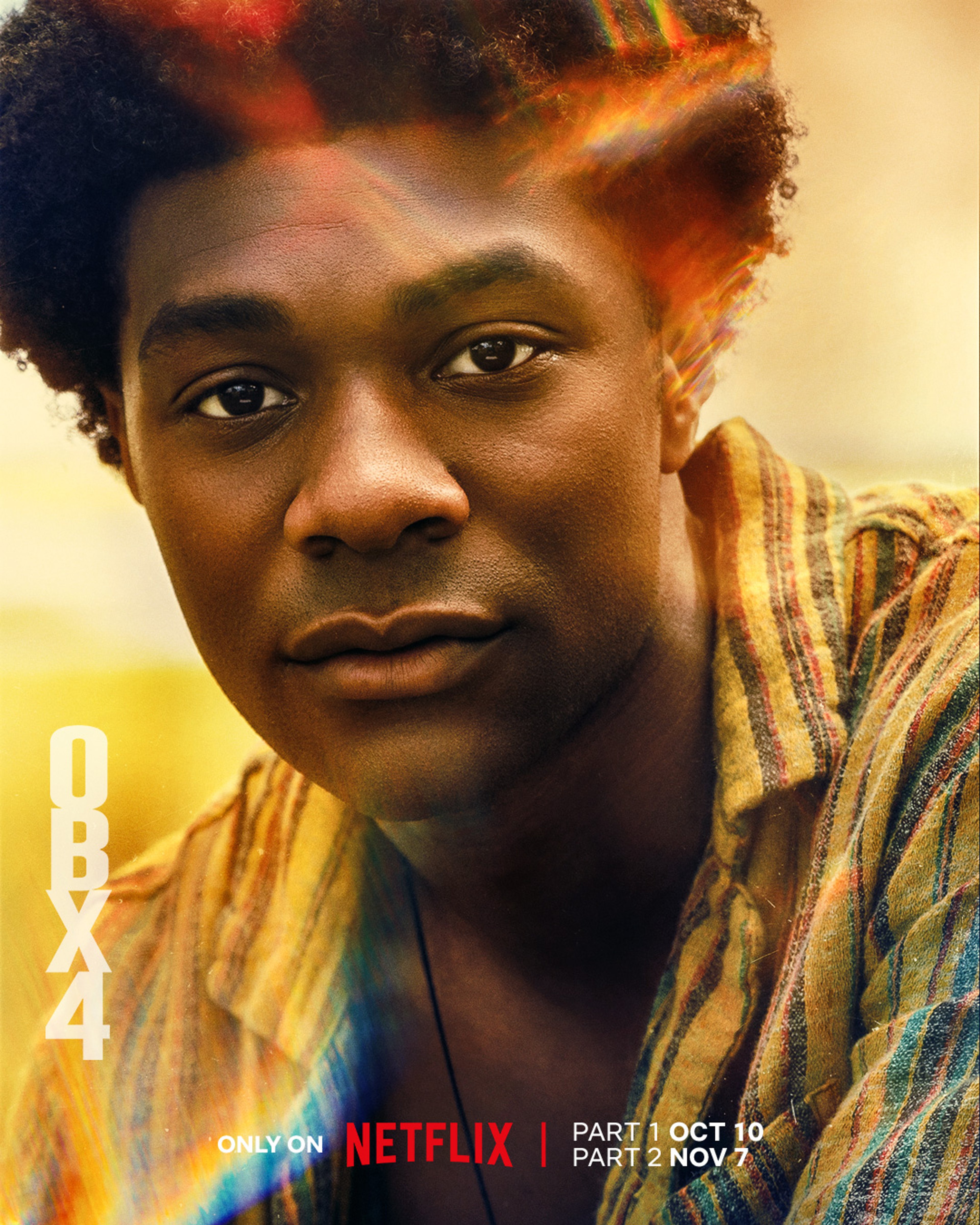 A young Black man with short, curly hair wearing a plaid shirt