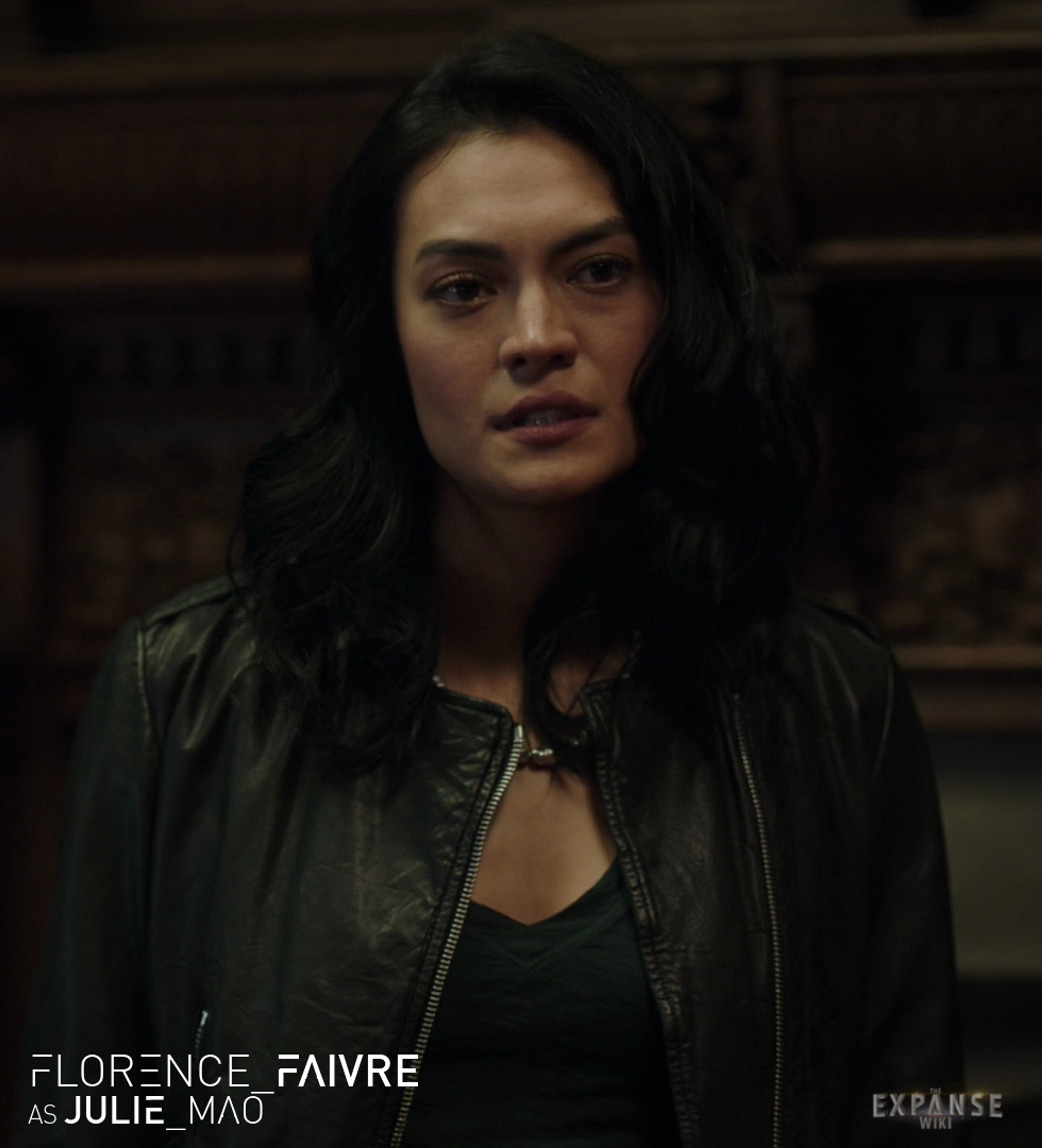 A woman with dark hair wearing a black top and leather jacket