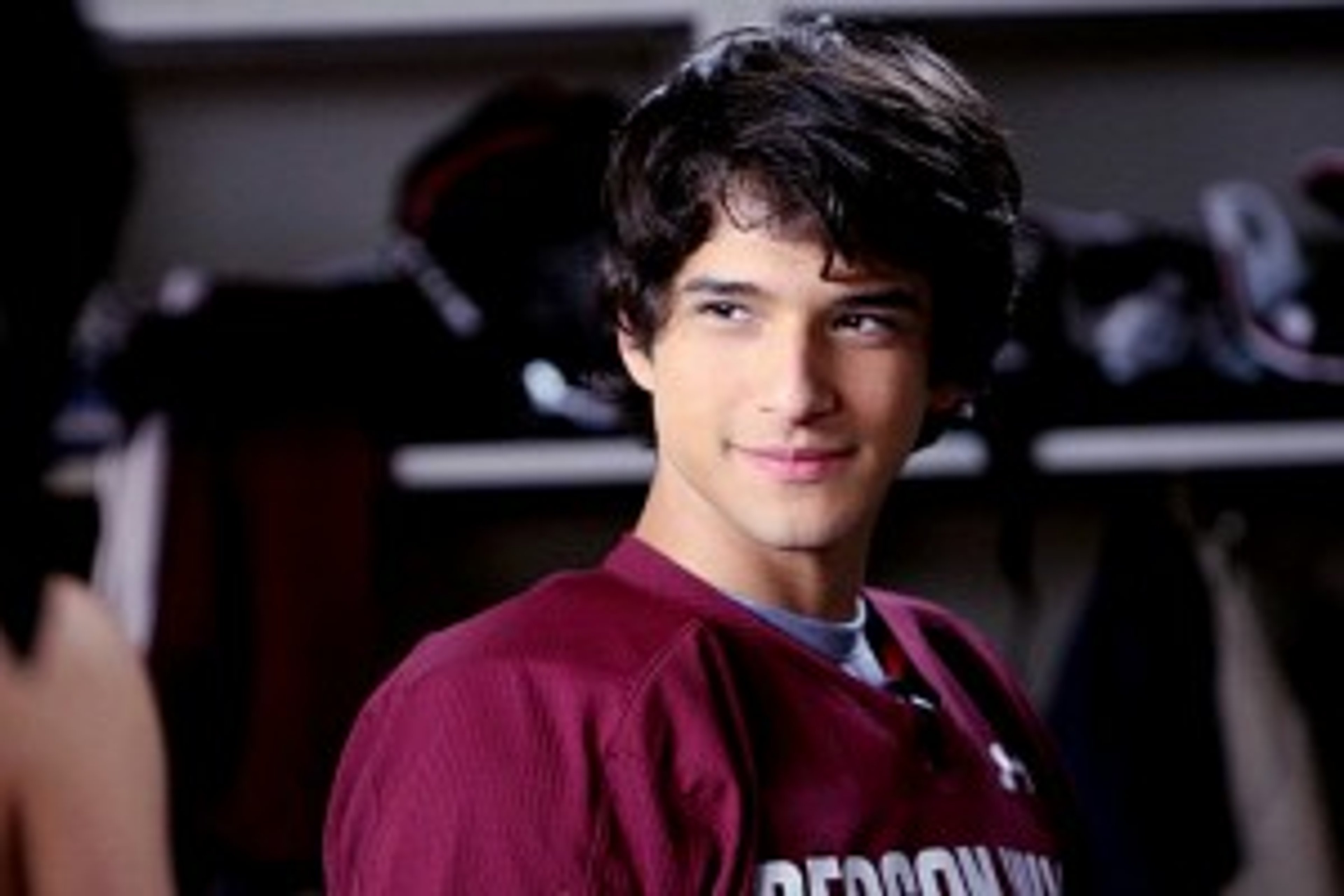 A young man with dark hair wearing a red t-shirt