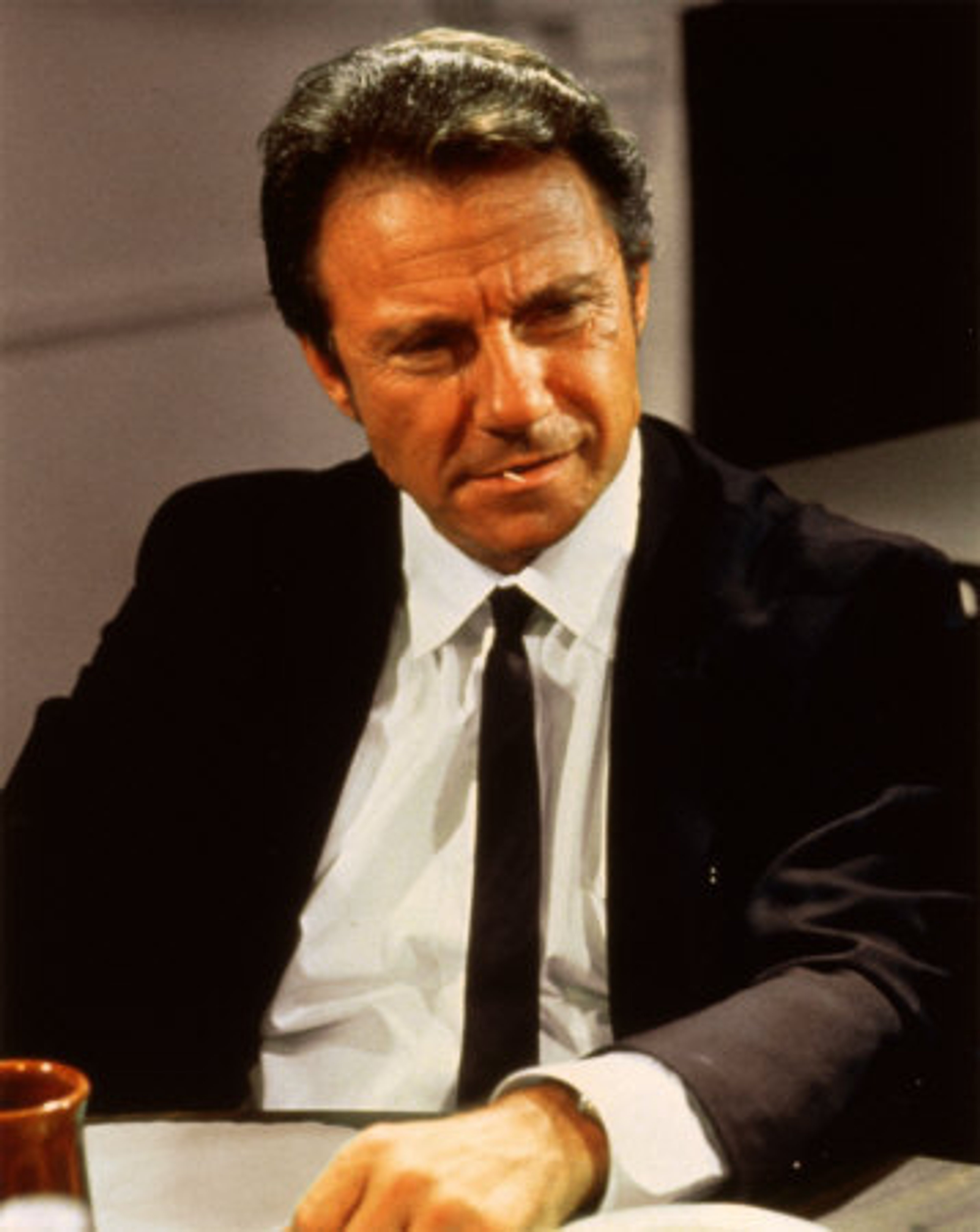 A middle-aged man in a suit and tie with a serious expression