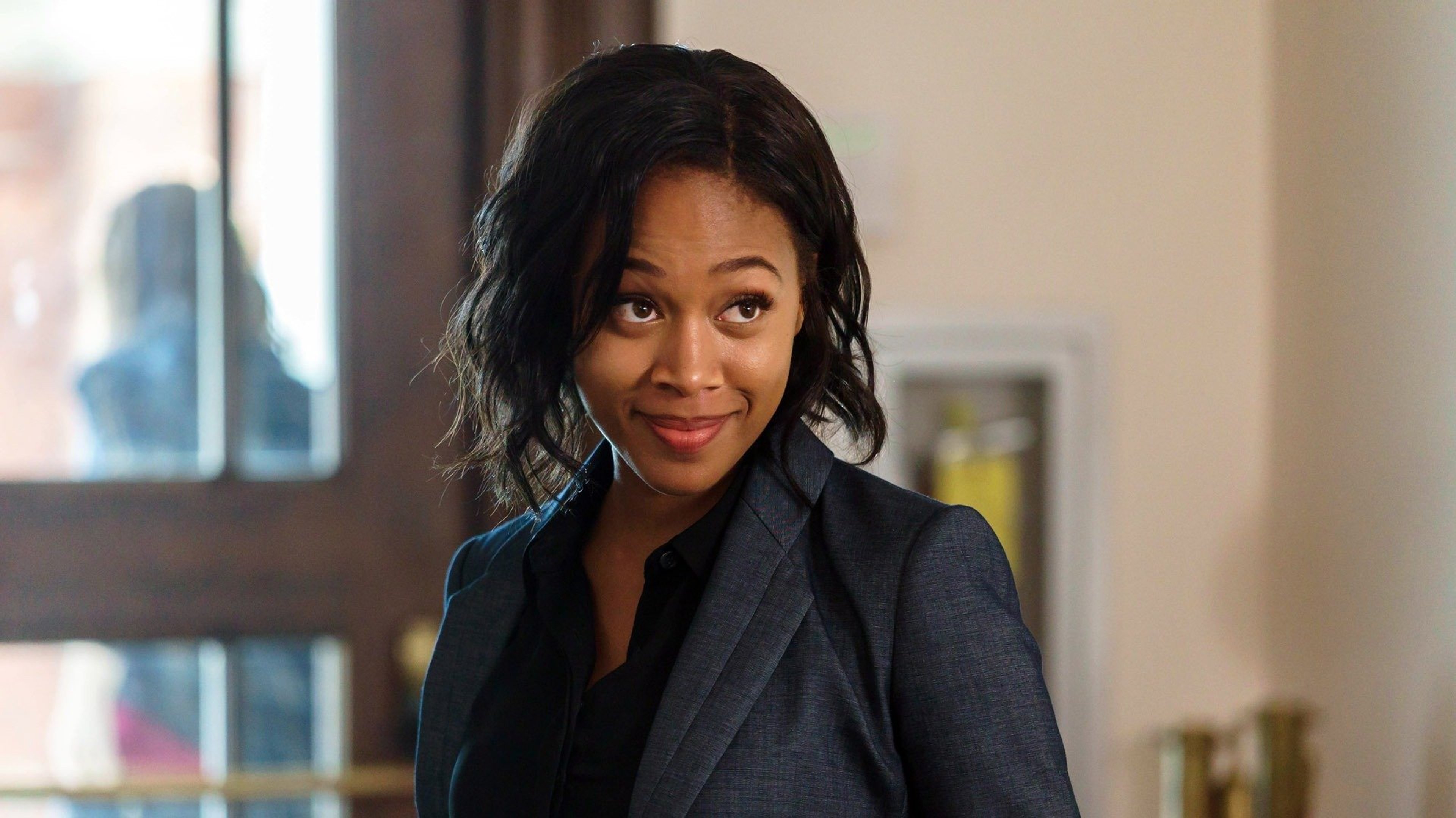 A woman in a black jacket with a serious expression