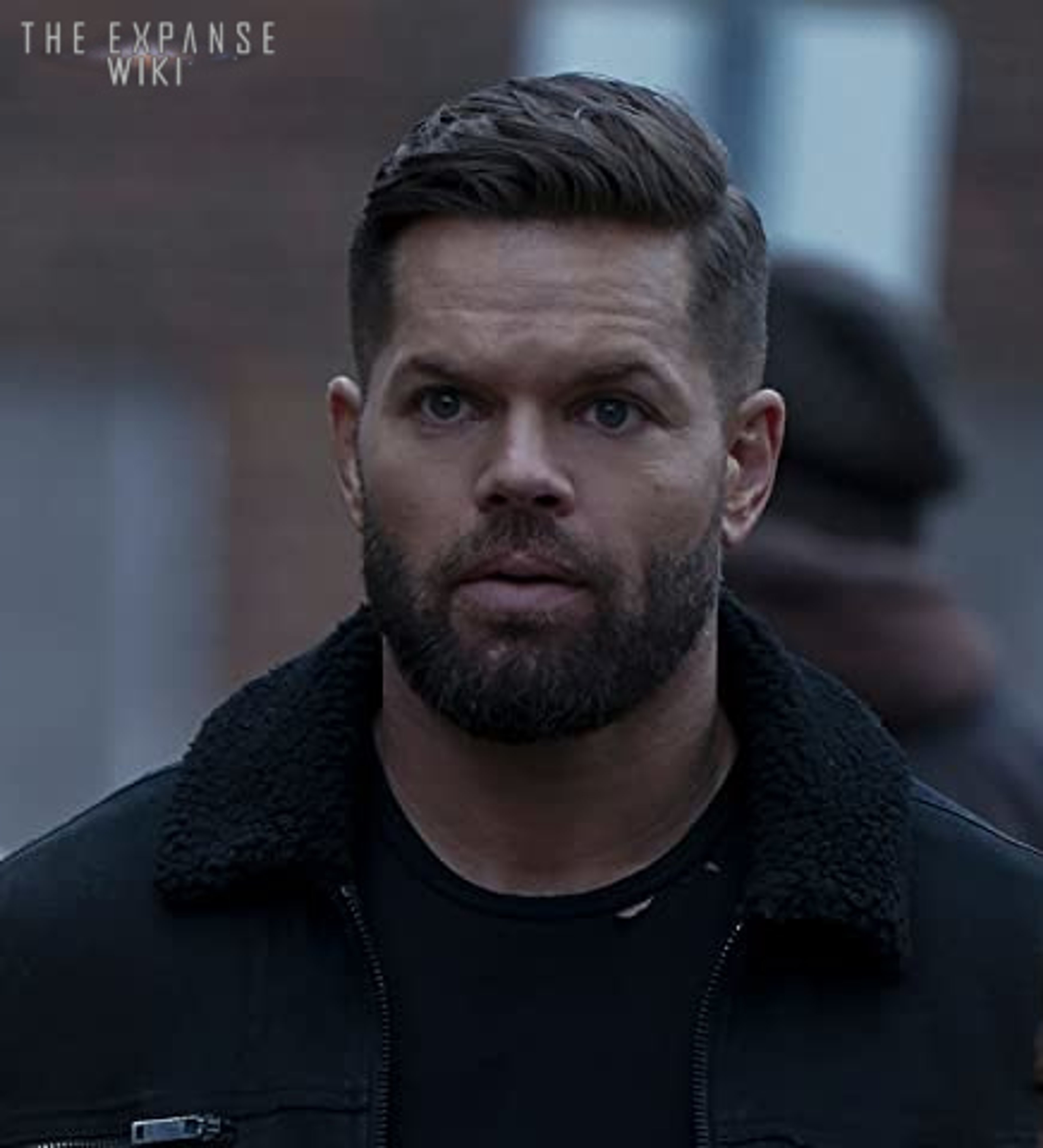 A middle-aged man with a beard wearing a black jacket