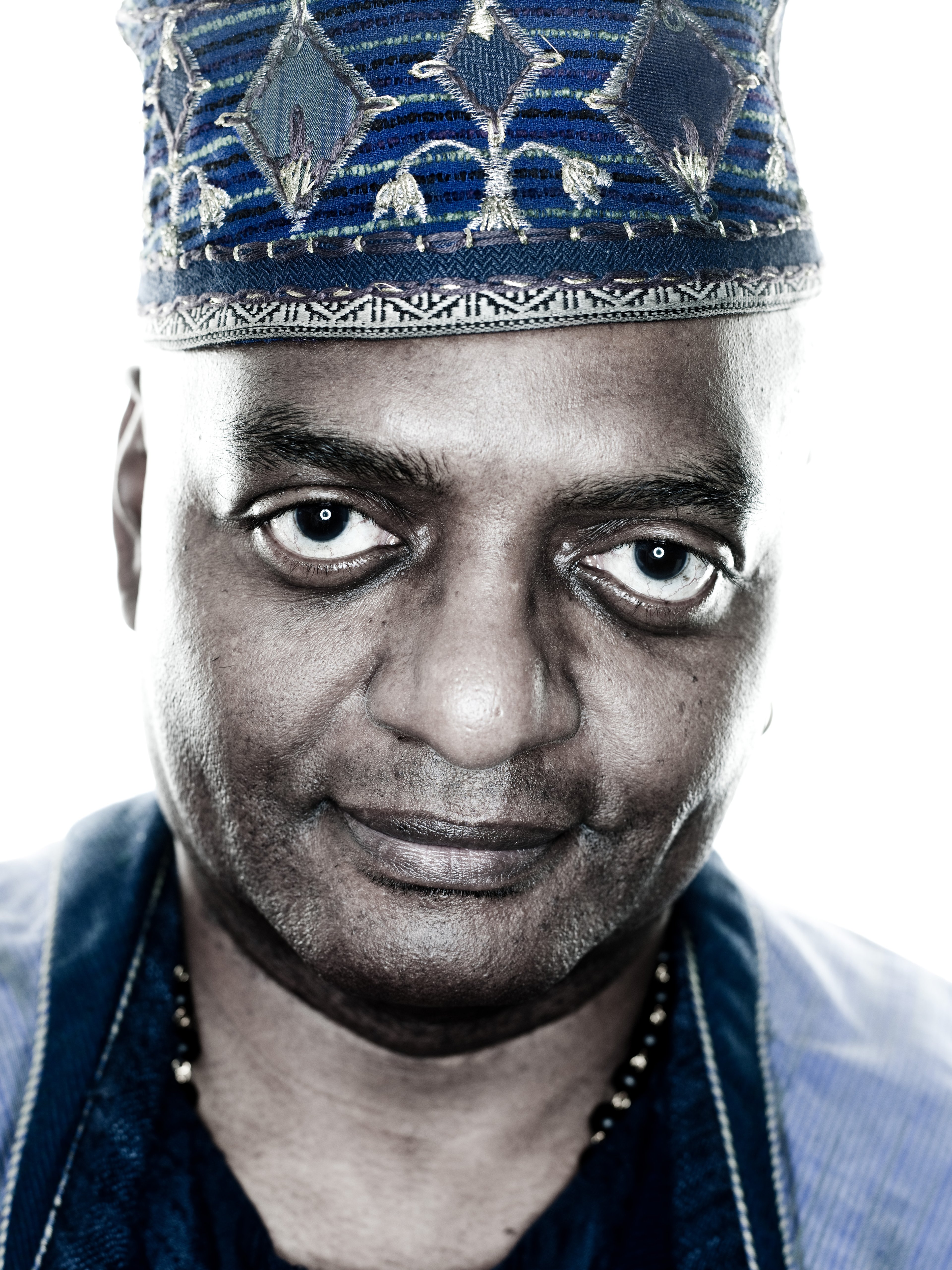 A middle-aged Black man wearing a patterned hat with a serious expression