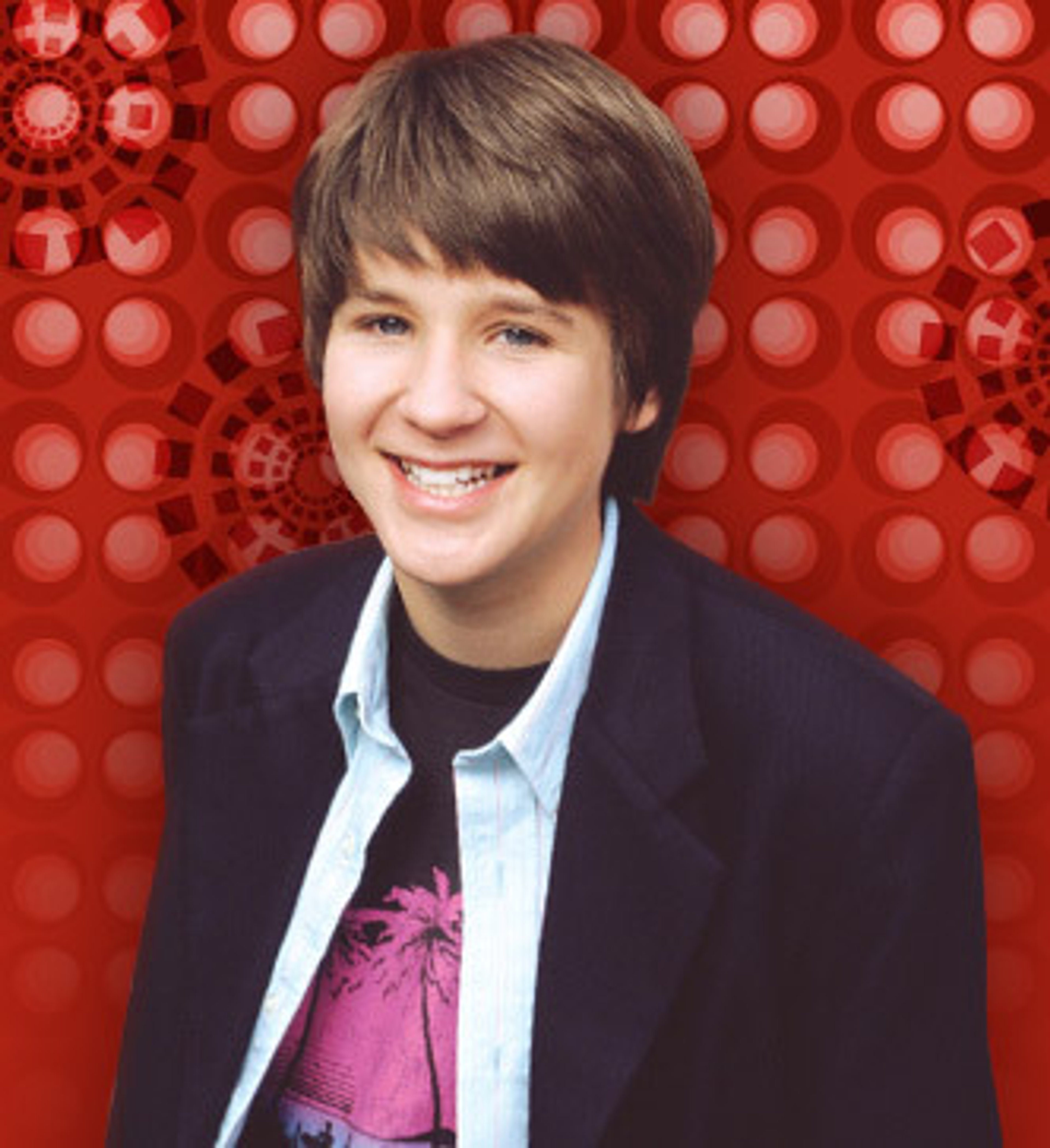 A smiling young boy with short dark hair wearing a navy blue jacket