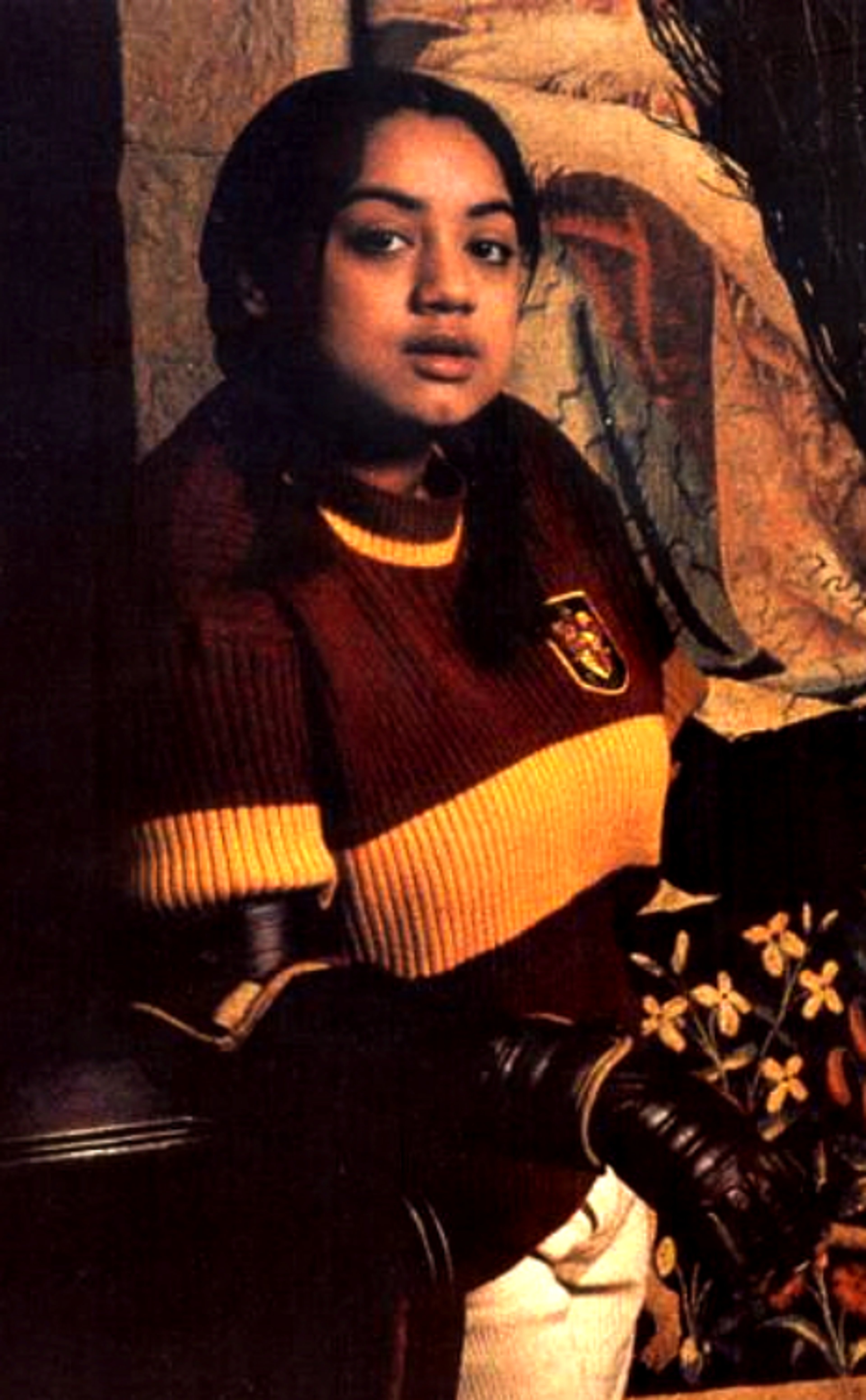 A young woman with dark hair wearing a red and yellow striped sweater