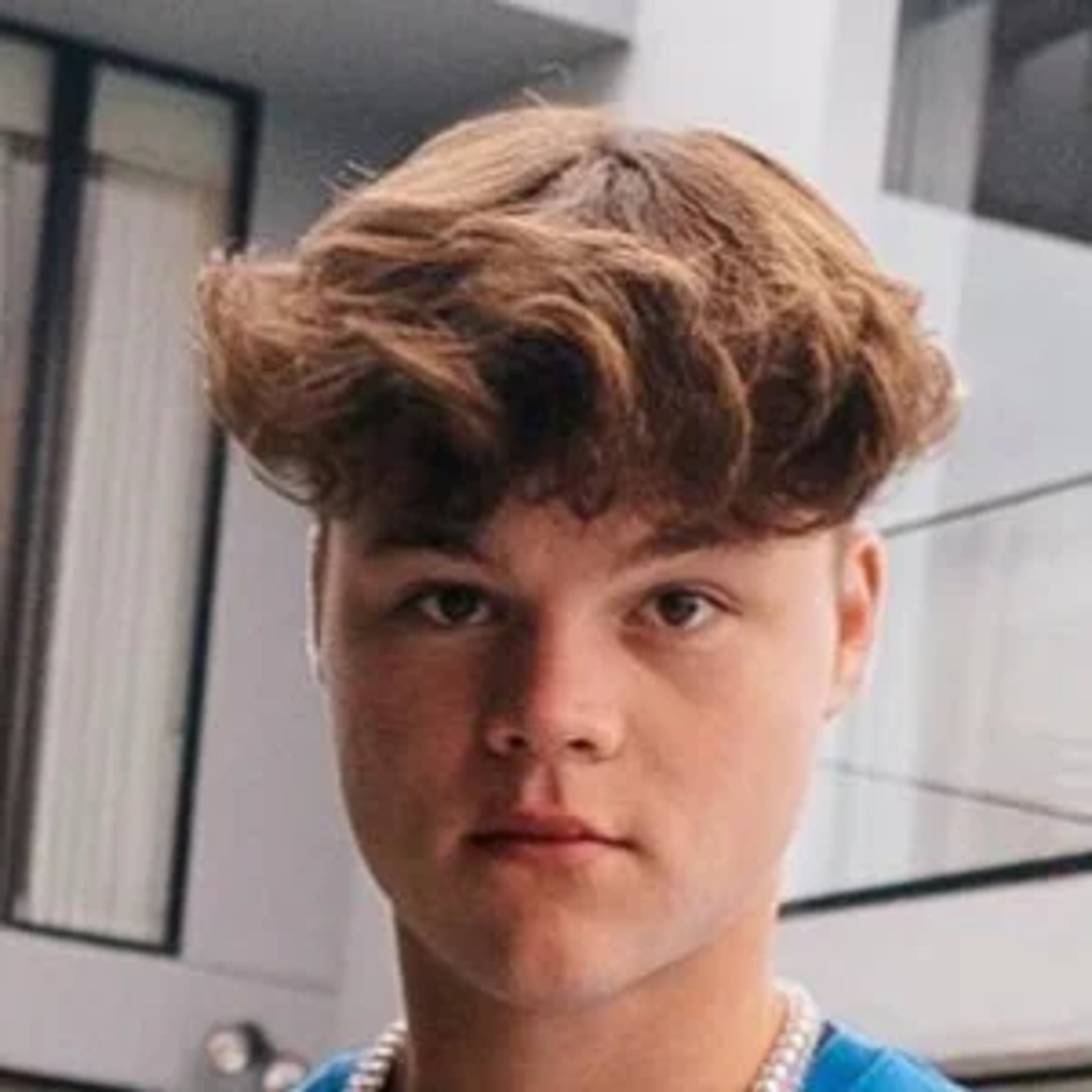 A young man with curly brown hair and a serious expression