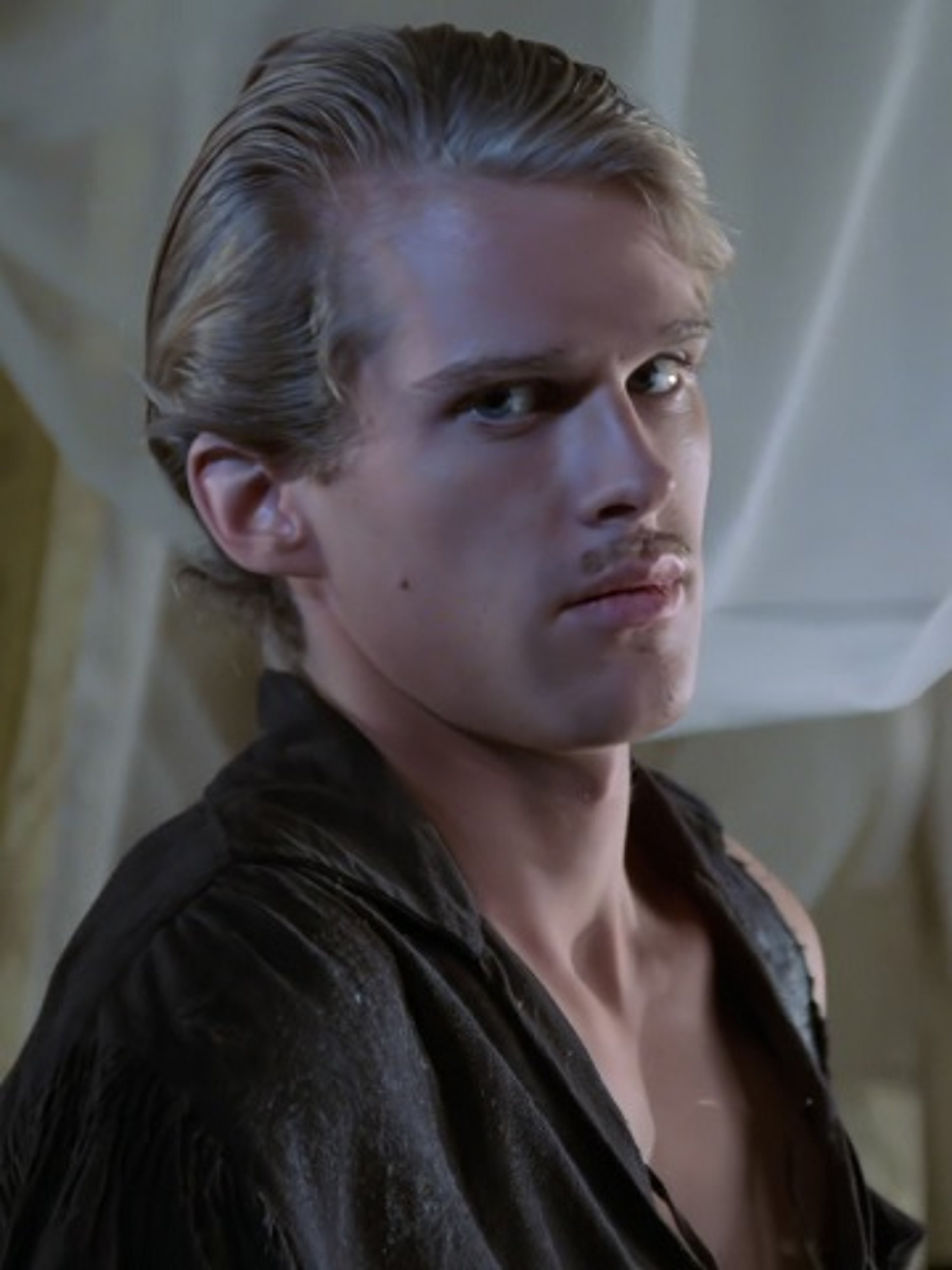 A young man with blond hair and a serious expression