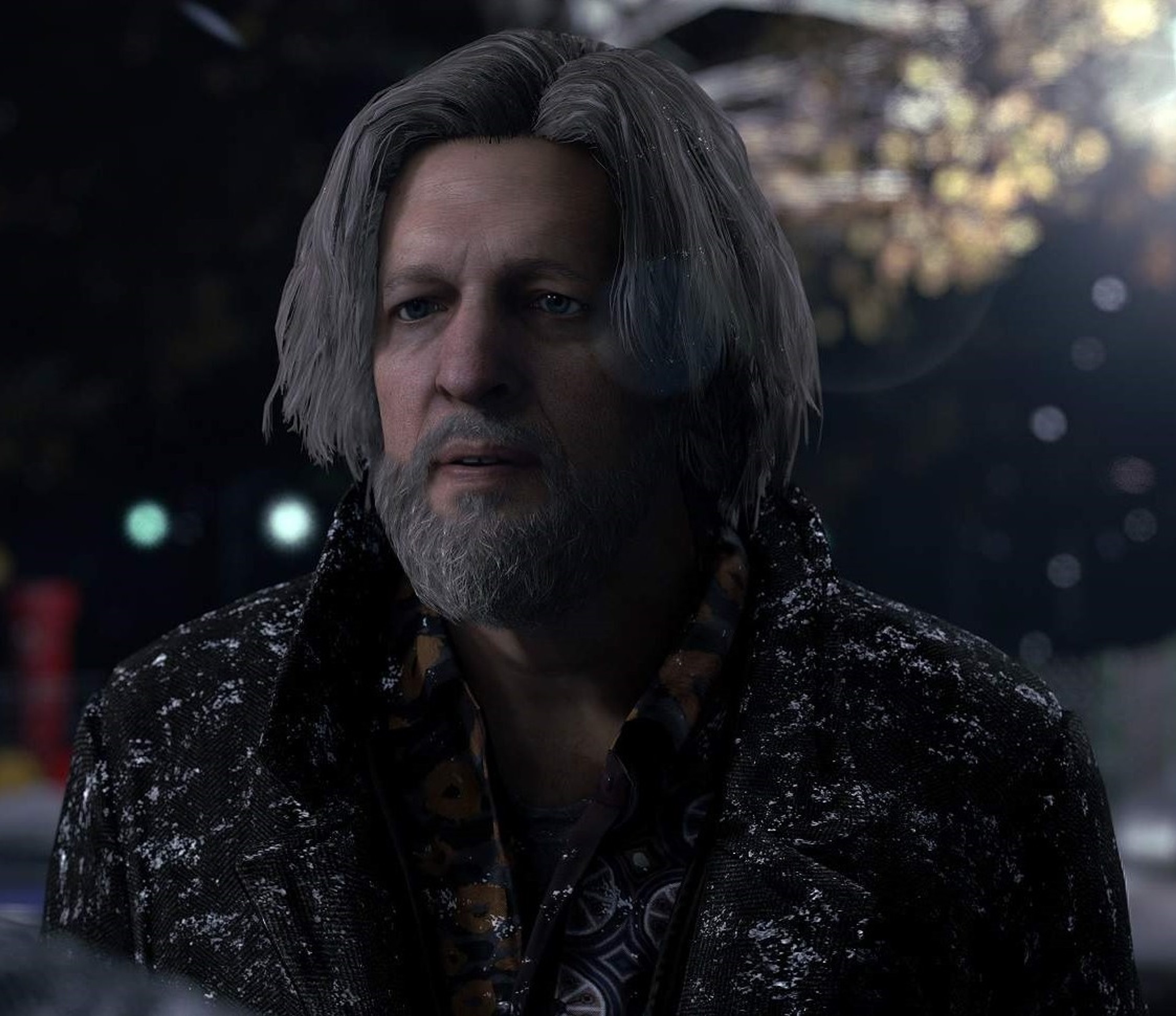A middle-aged man with long, graying hair and a scruffy beard wearing a dark, patterned jacket
