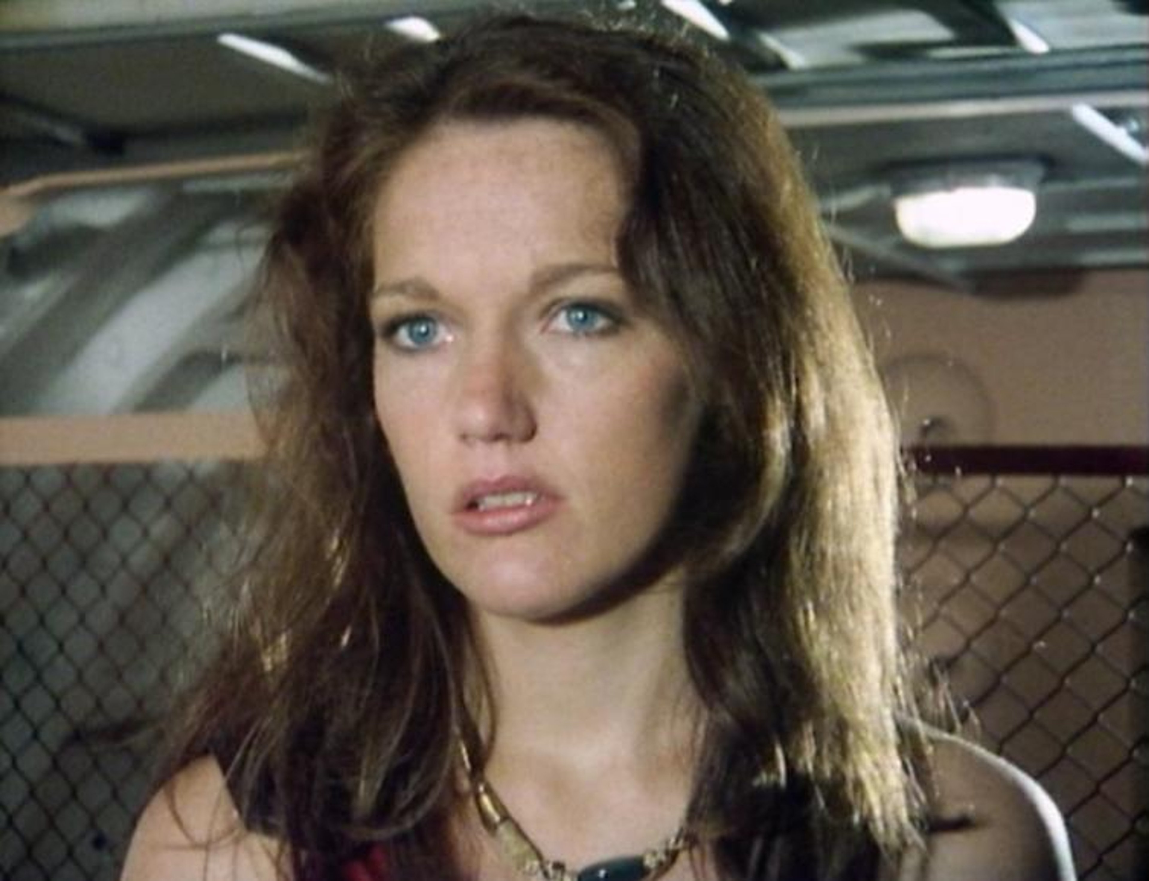 A fierce-looking woman with long dark hair and intense eyes, wearing tribal-style clothing.