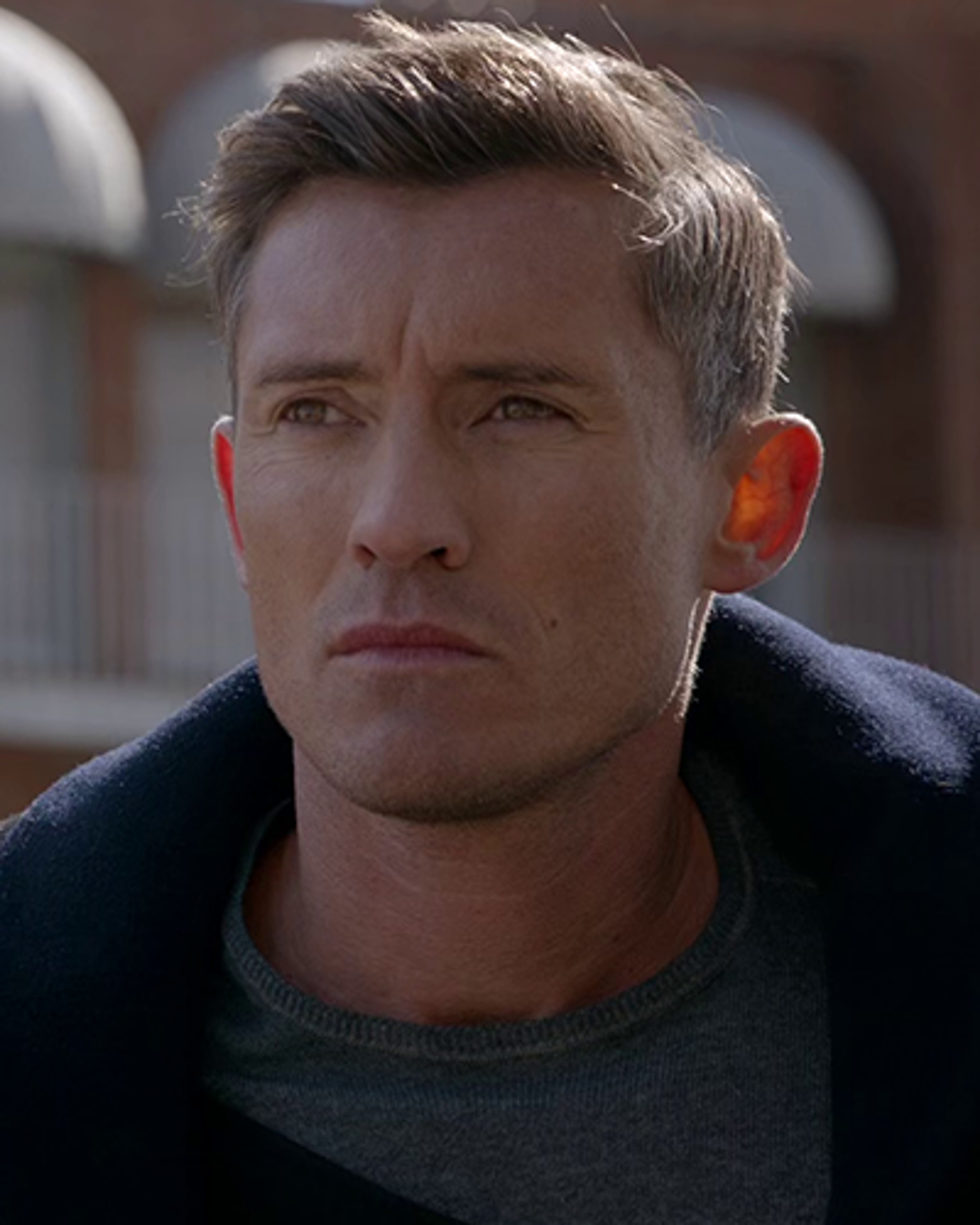 A man with short, light brown hair and a serious expression