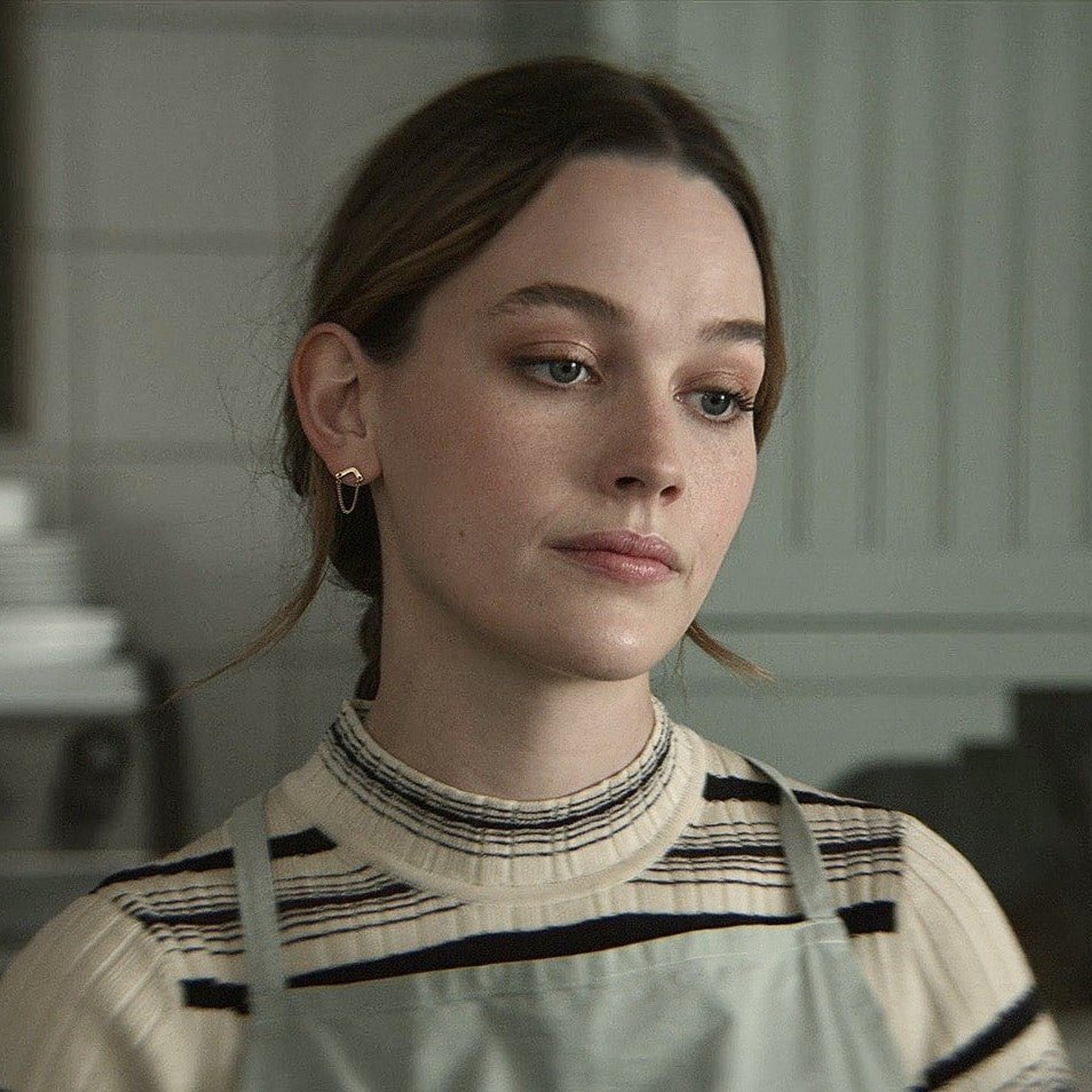 A young woman with brown hair wearing a striped sweater