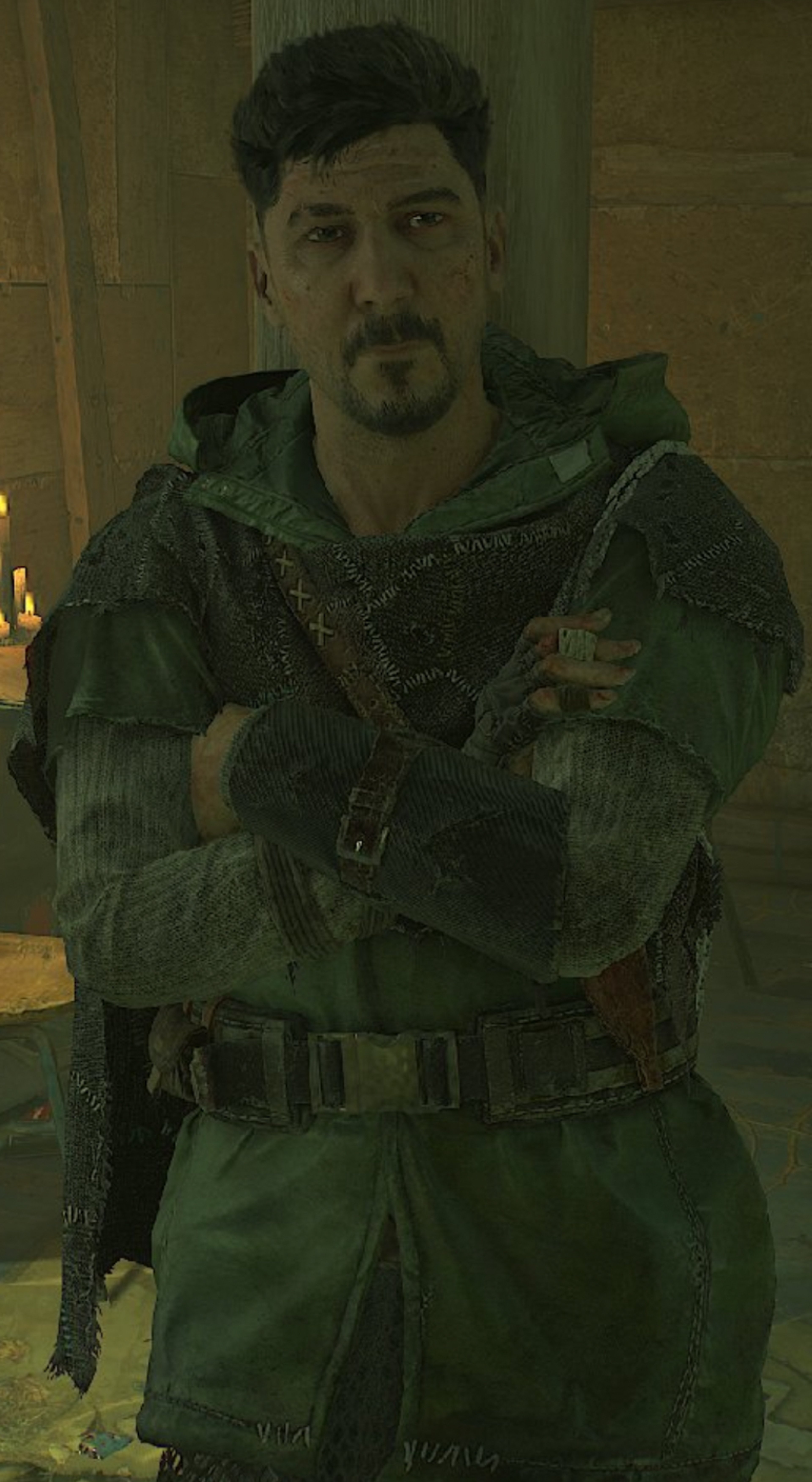 A man in a military-style green raincoat and black cloak, with a rugged, weathered appearance.