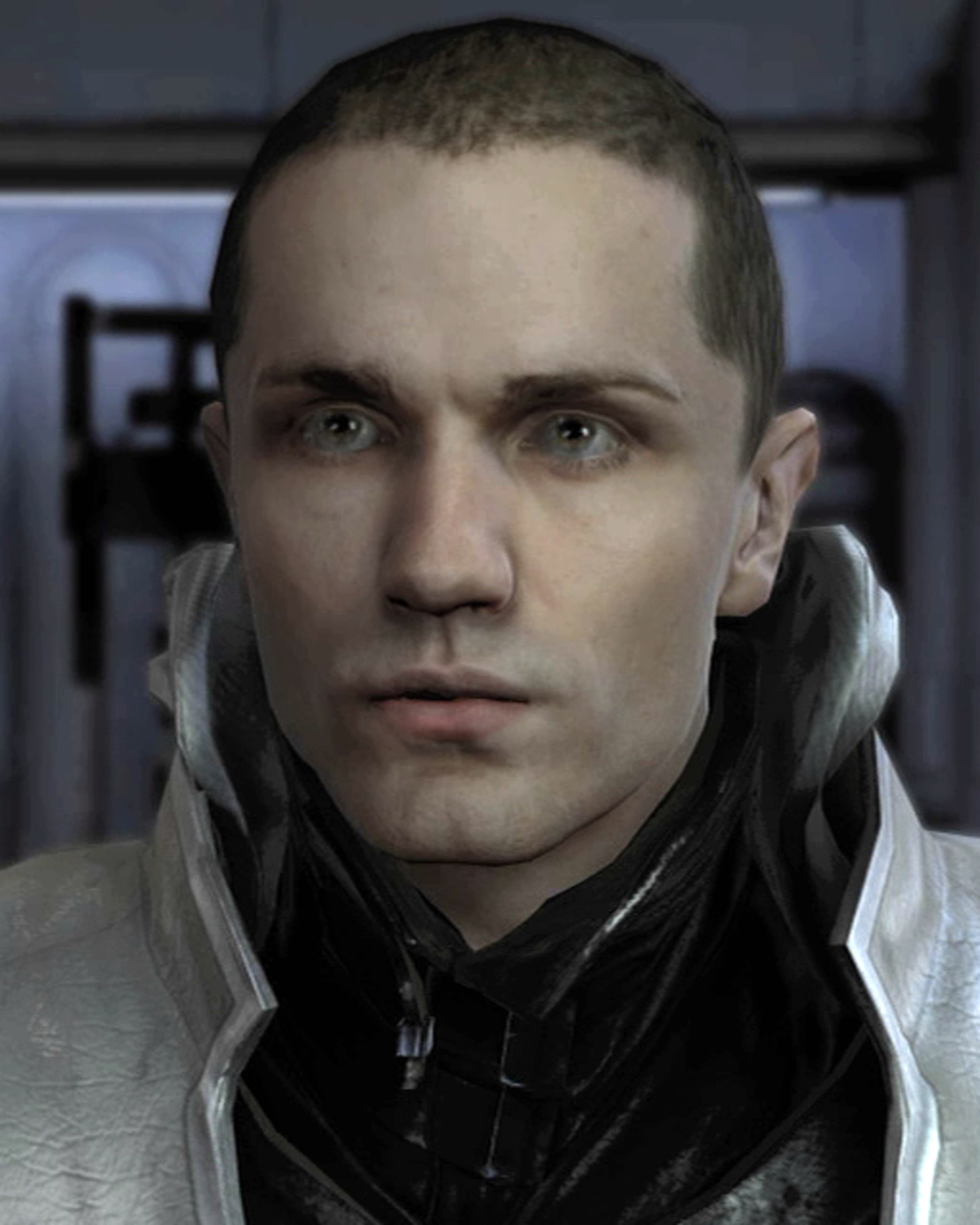 A young man with short dark hair wearing a dark jacket, with a serious expression