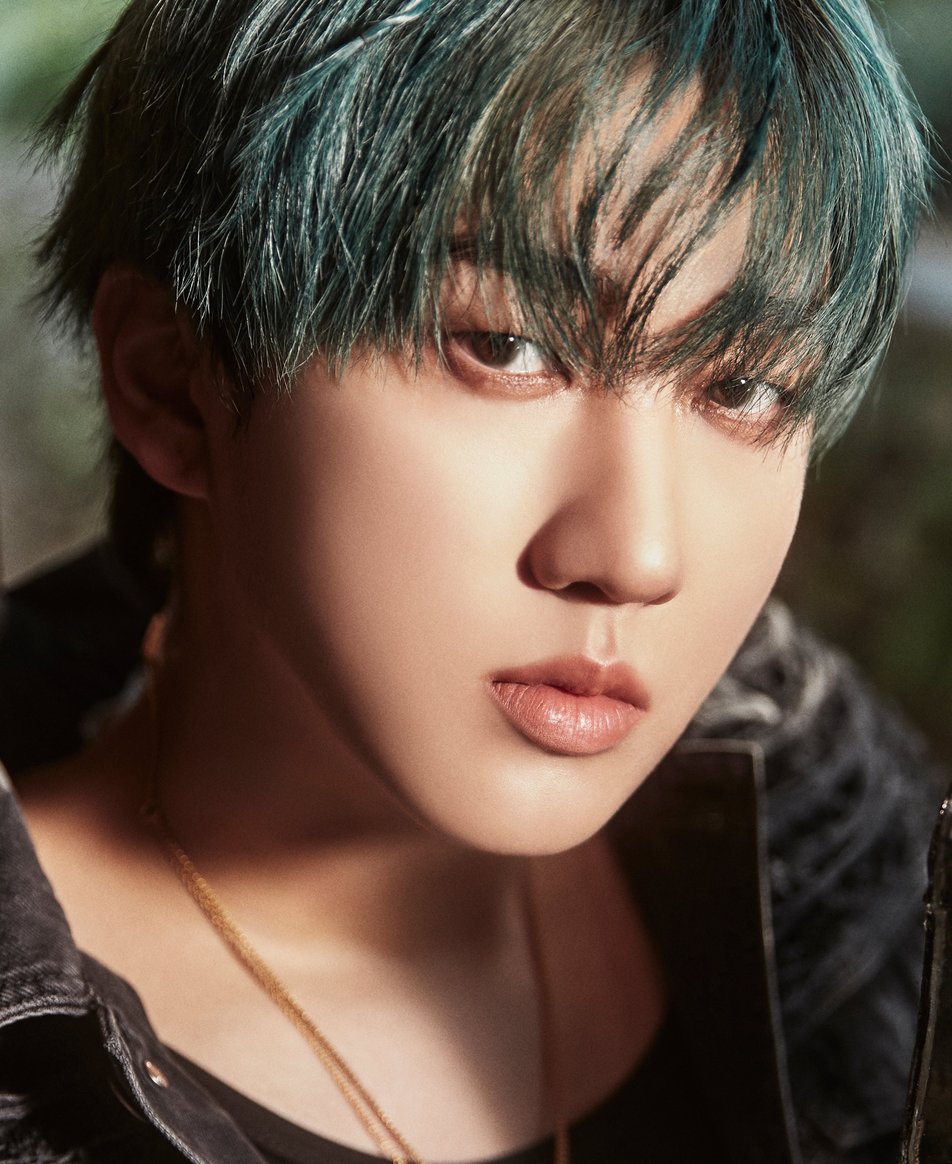 A young man with dark hair and a serious expression, wearing a black jacket.