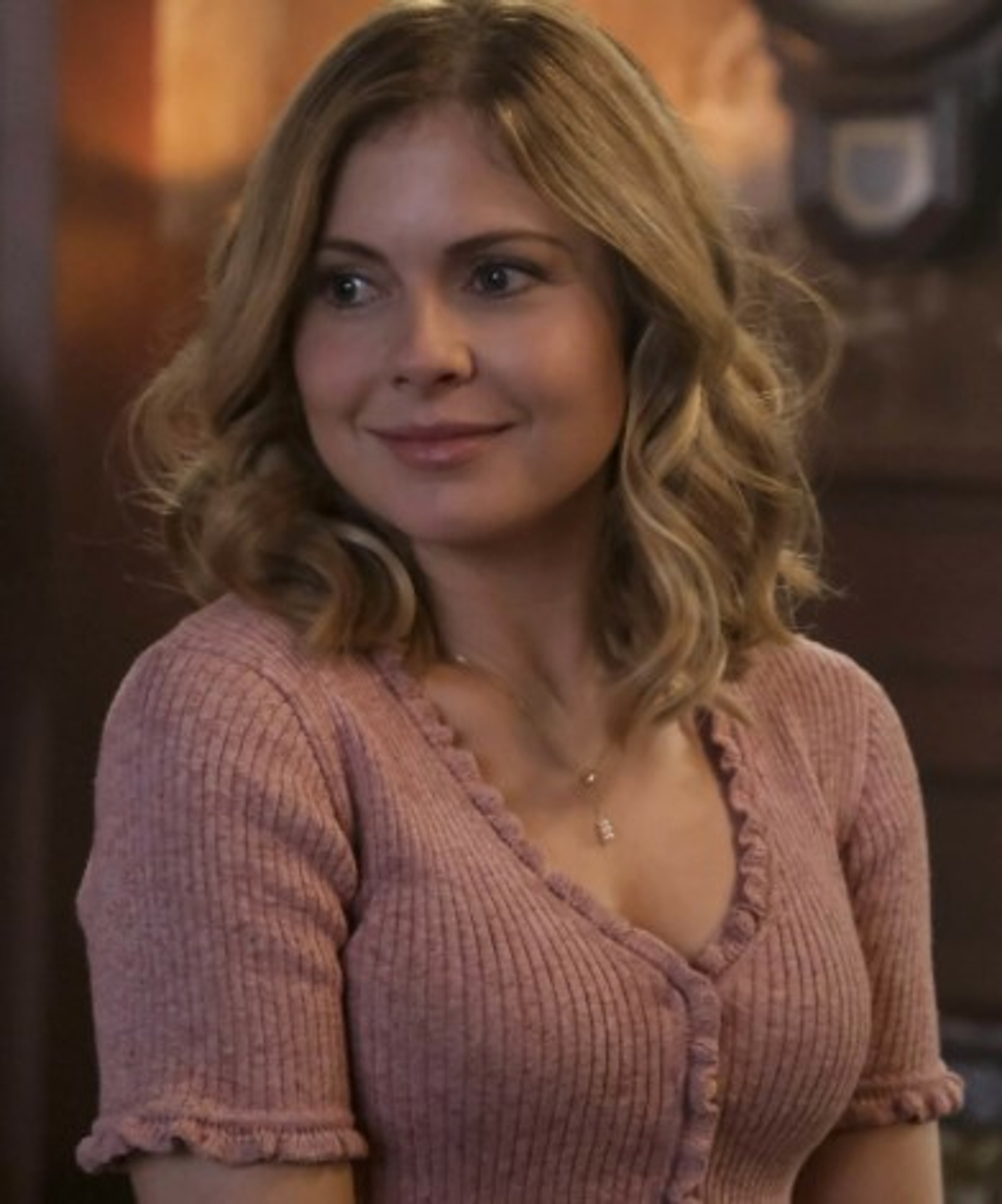 A smiling woman with long blonde hair wearing a light pink sweater