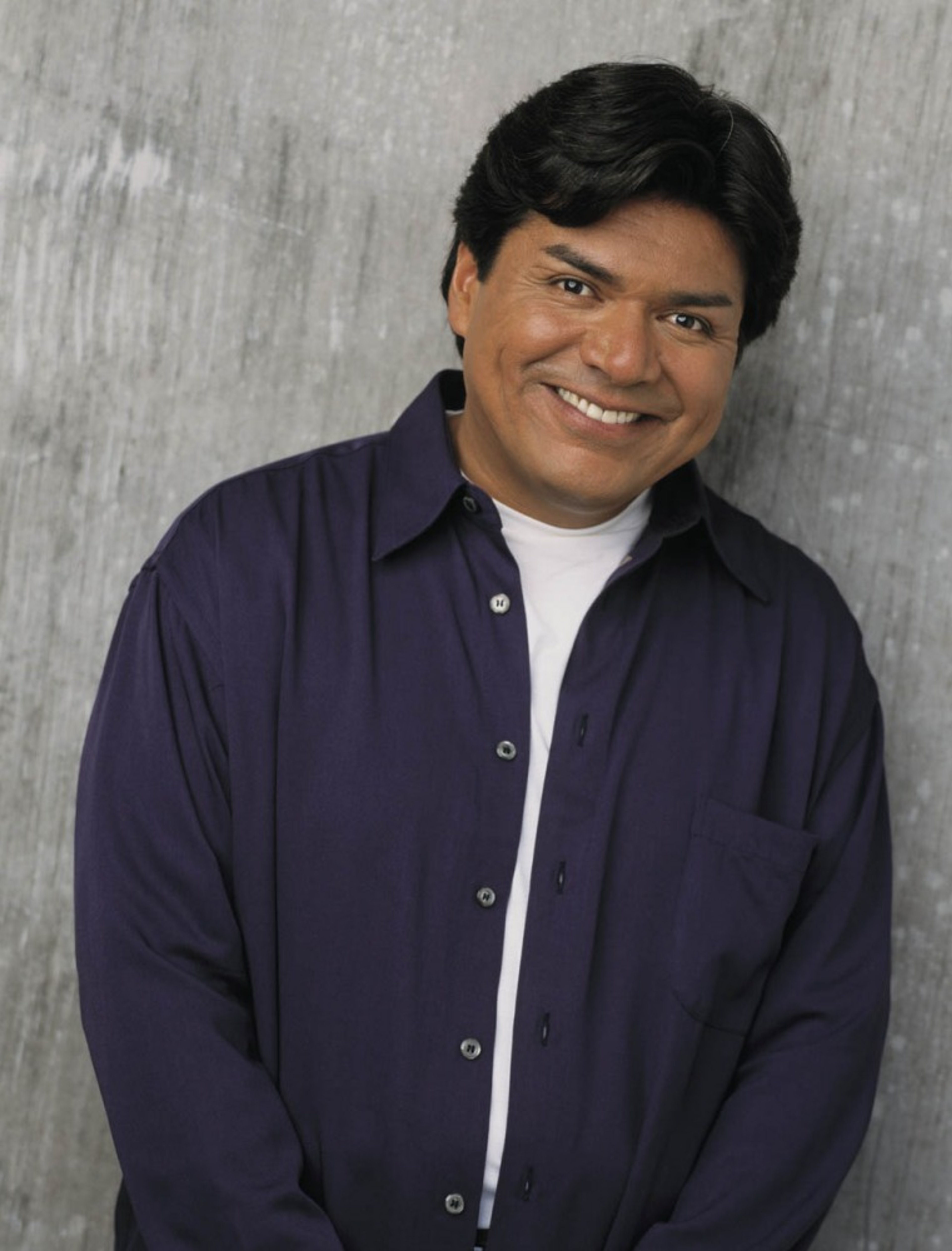 A middle-aged man with dark hair and a friendly smile, wearing a purple shirt.