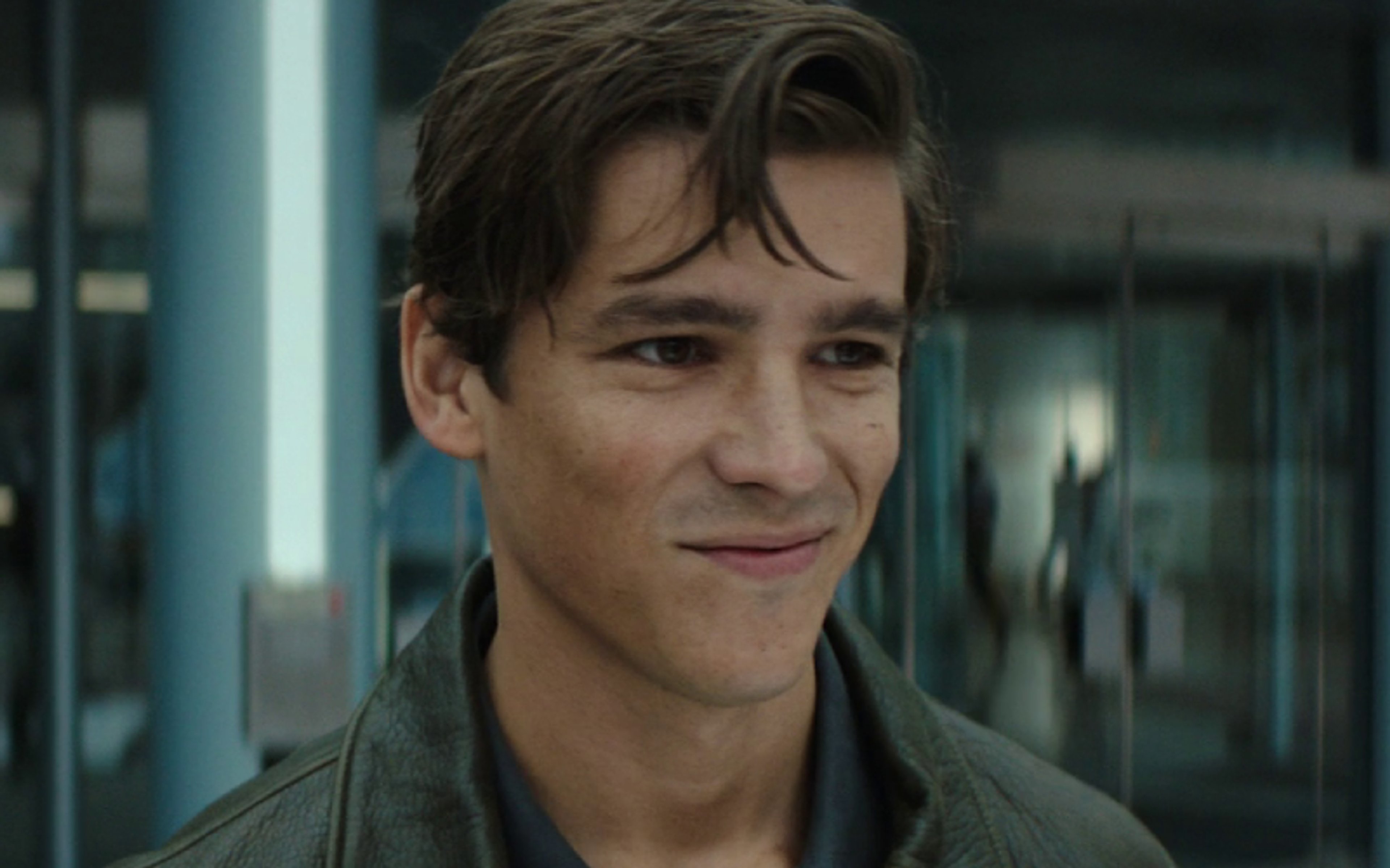 A young man with dark hair wearing a green jacket
