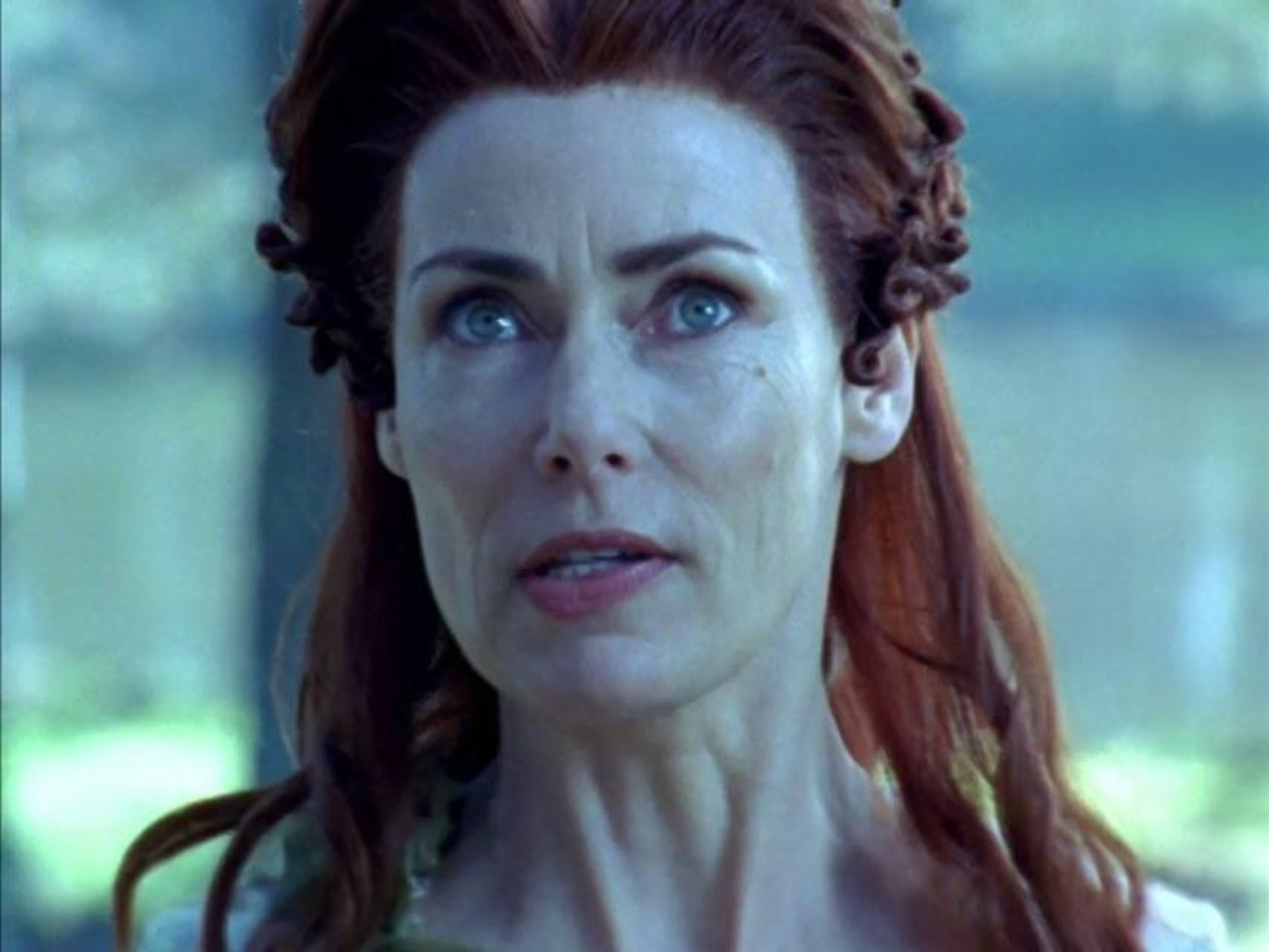 A powerful sorceress with long red hair and blue eyes wearing a white and blue magical robe