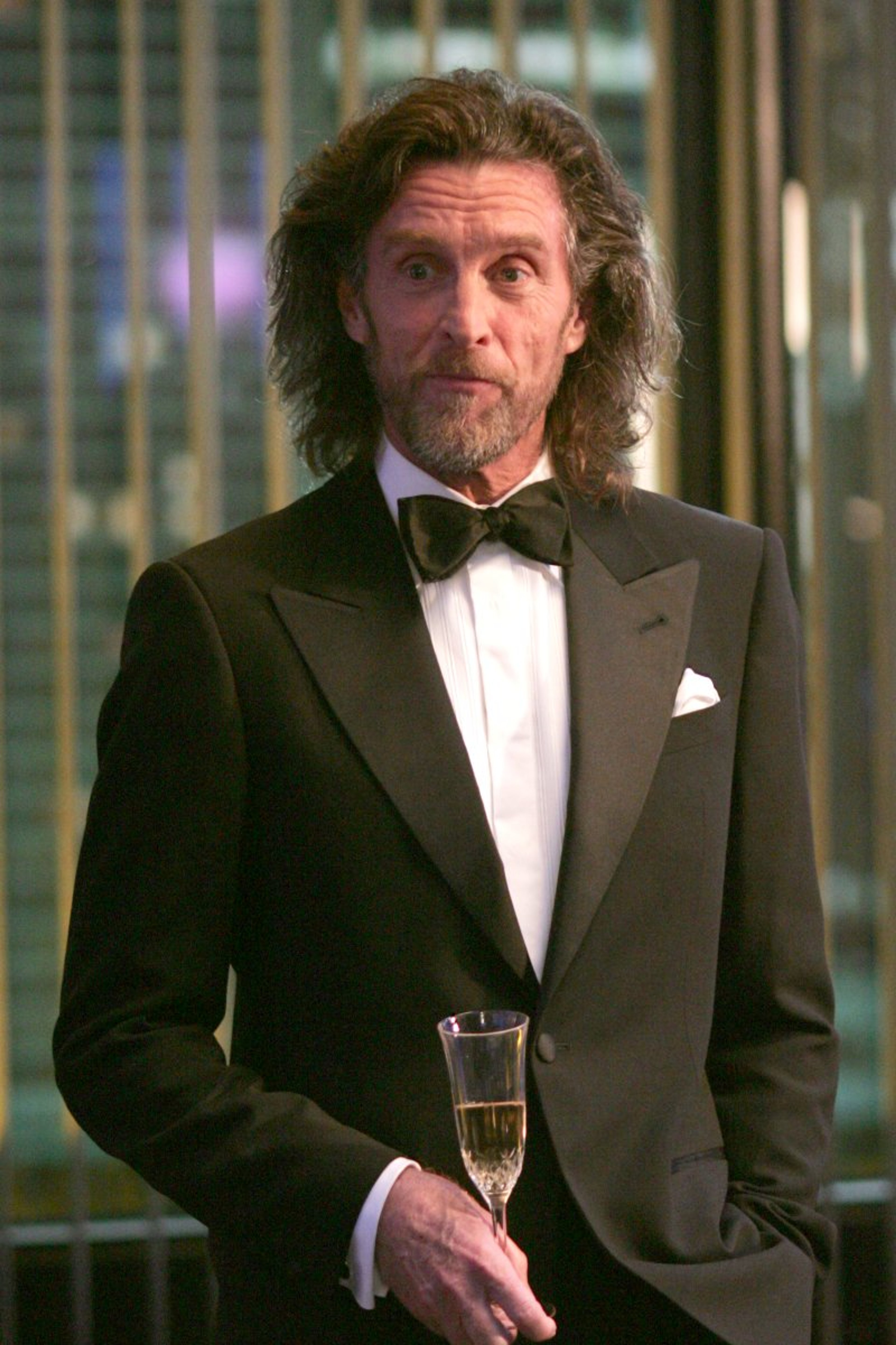 A well-dressed older man in a tuxedo holding a glass of champagne