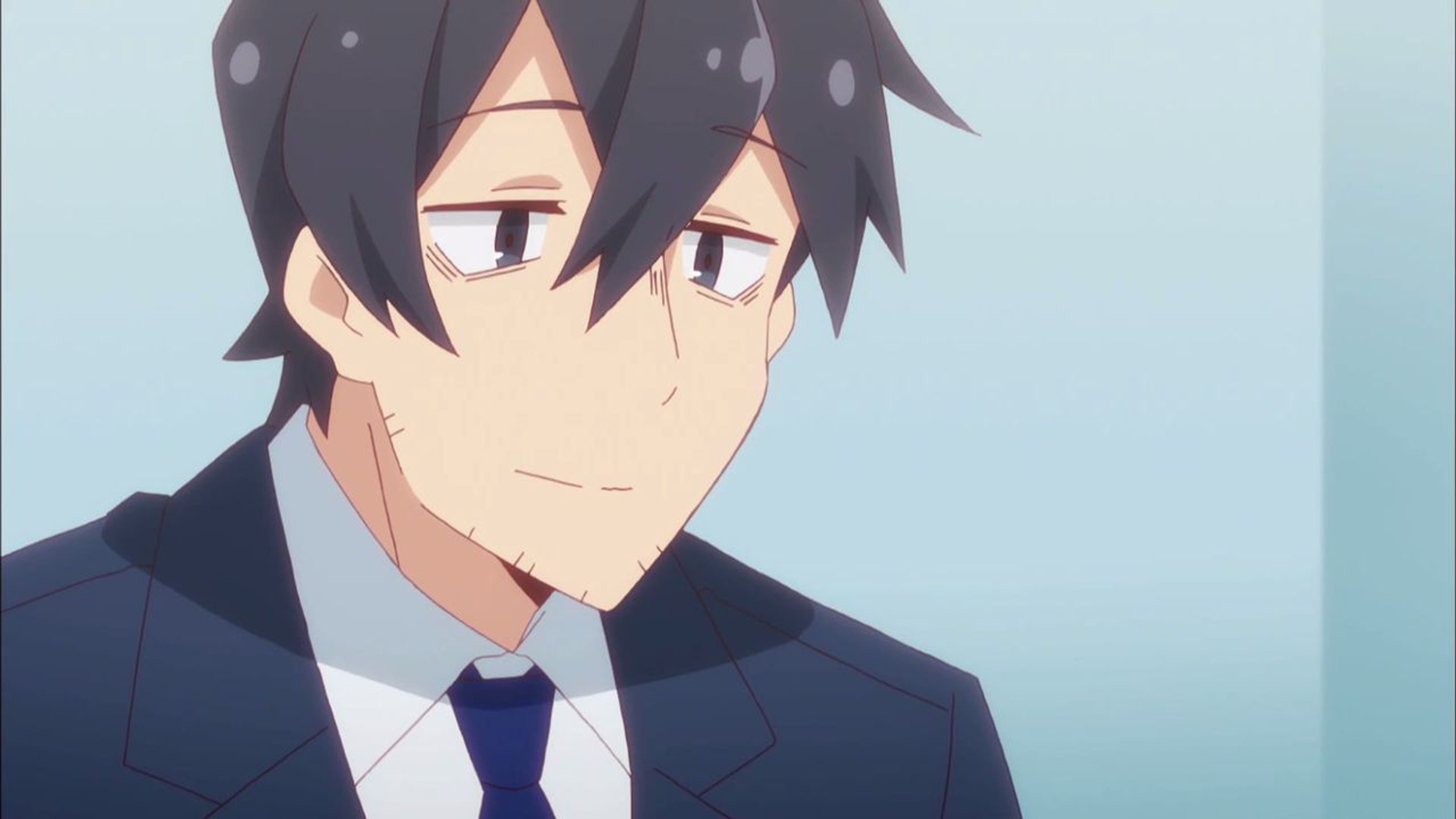 A young Japanese man in his 30s with unkempt black hair and a tired expression, wearing a blue suit jacket and tie.