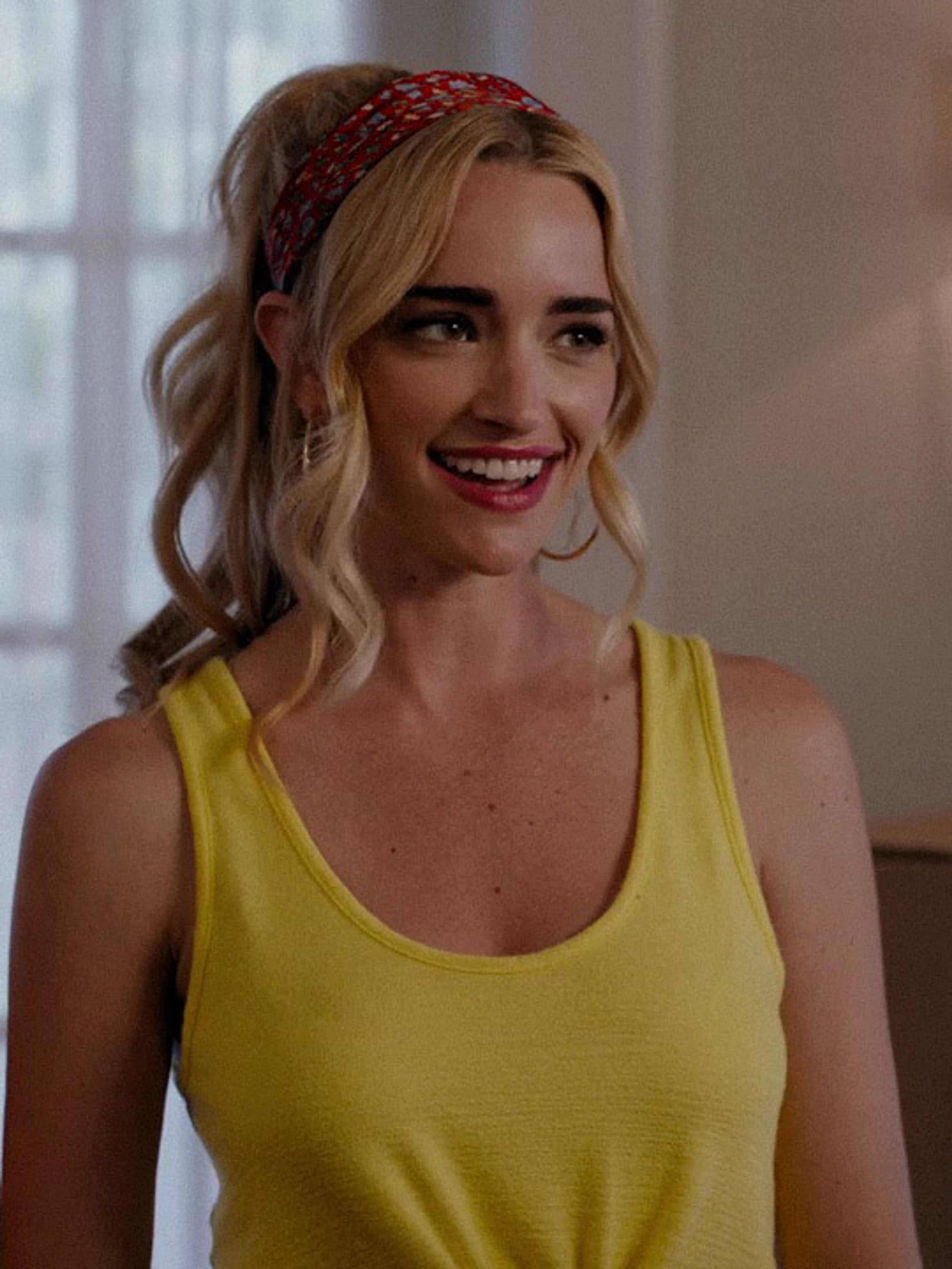 A smiling blonde woman in a yellow tank top