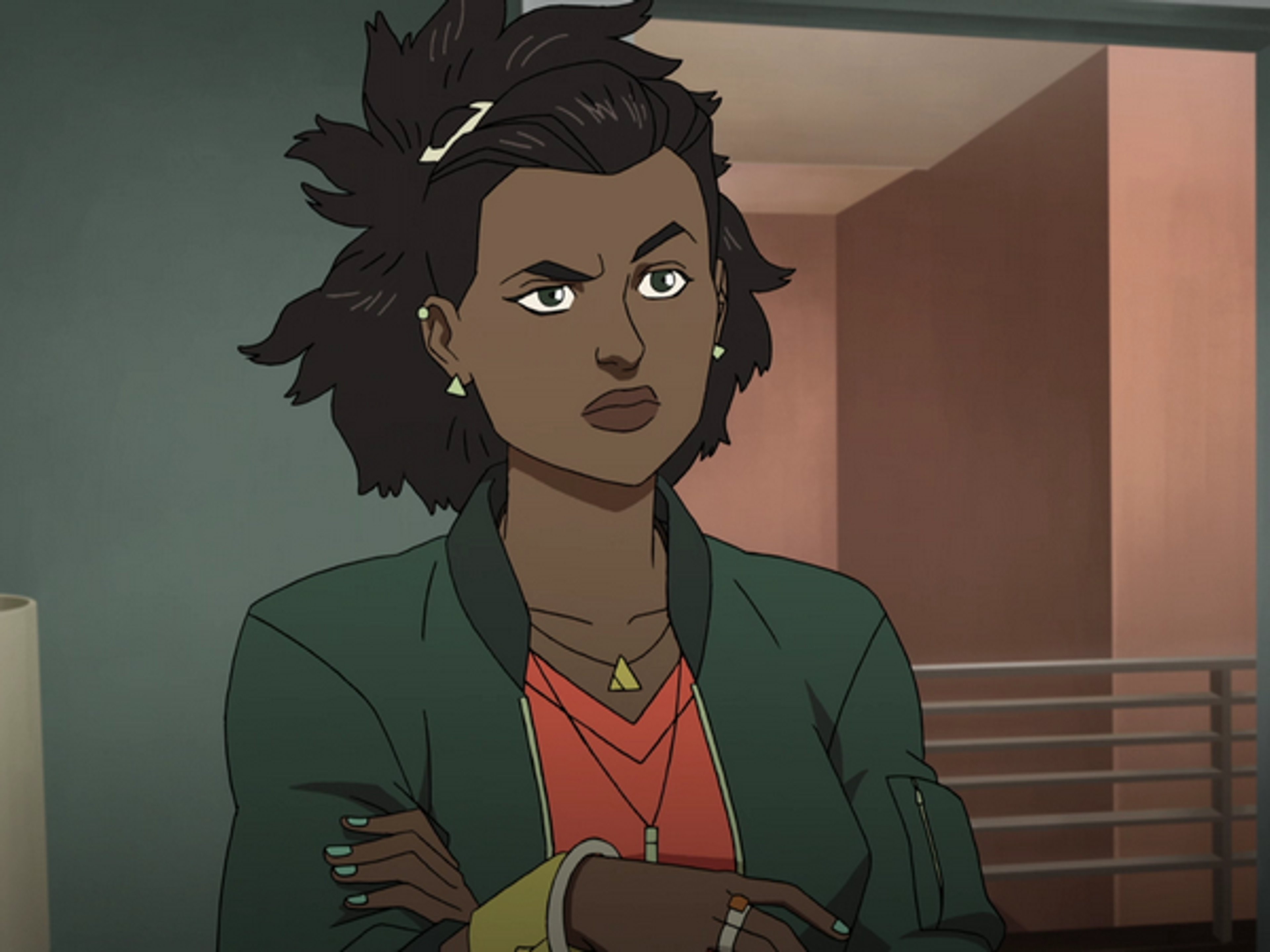 A young woman with dark curly hair wearing a green jacket and red shirt